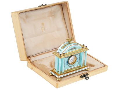 RUSSIAN SILVER GUILLOCHE ENAMEL DIAMONDS CLOCK IOB: A miniature Russian silver clock decorated with guilloche enamel. The clock has a light blue enamel, adorned with painted floral accents with a blue ribbon. There are columns that support the hood. Th
