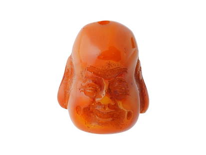 ANTIQUE ASIAN AMBER PENDANT OF A LAUGHING BUDDHA: An antique Asian amber pendant carved in the form of a laughing Buddha, dating to the early 1900s. Skillfully worked from warm-toned amber, the figure is depicted with joyful expression and characteri