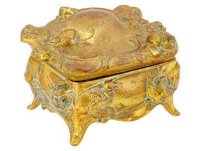 ANTIQUE VICTORIAN GILT METAL TRINKET OR JEWELRY BOX: An antique Victorian gilt metal trinket or jewelry box. The ornate box with a hinged lid is decorated with a lush relief pattern of roses over the entire surface. Raised on four legs. Upholstery in bl