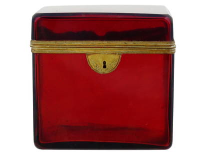 EUROPEAN RUBY RED GLASS BOX W GILT BRASS FITTING: An European glass box in ruby red color with gilt brass fitting. Presumably of Hungarian origin. The box has a rectangular shape with a hinged lid. It is made of transparent ruby colored glass and has