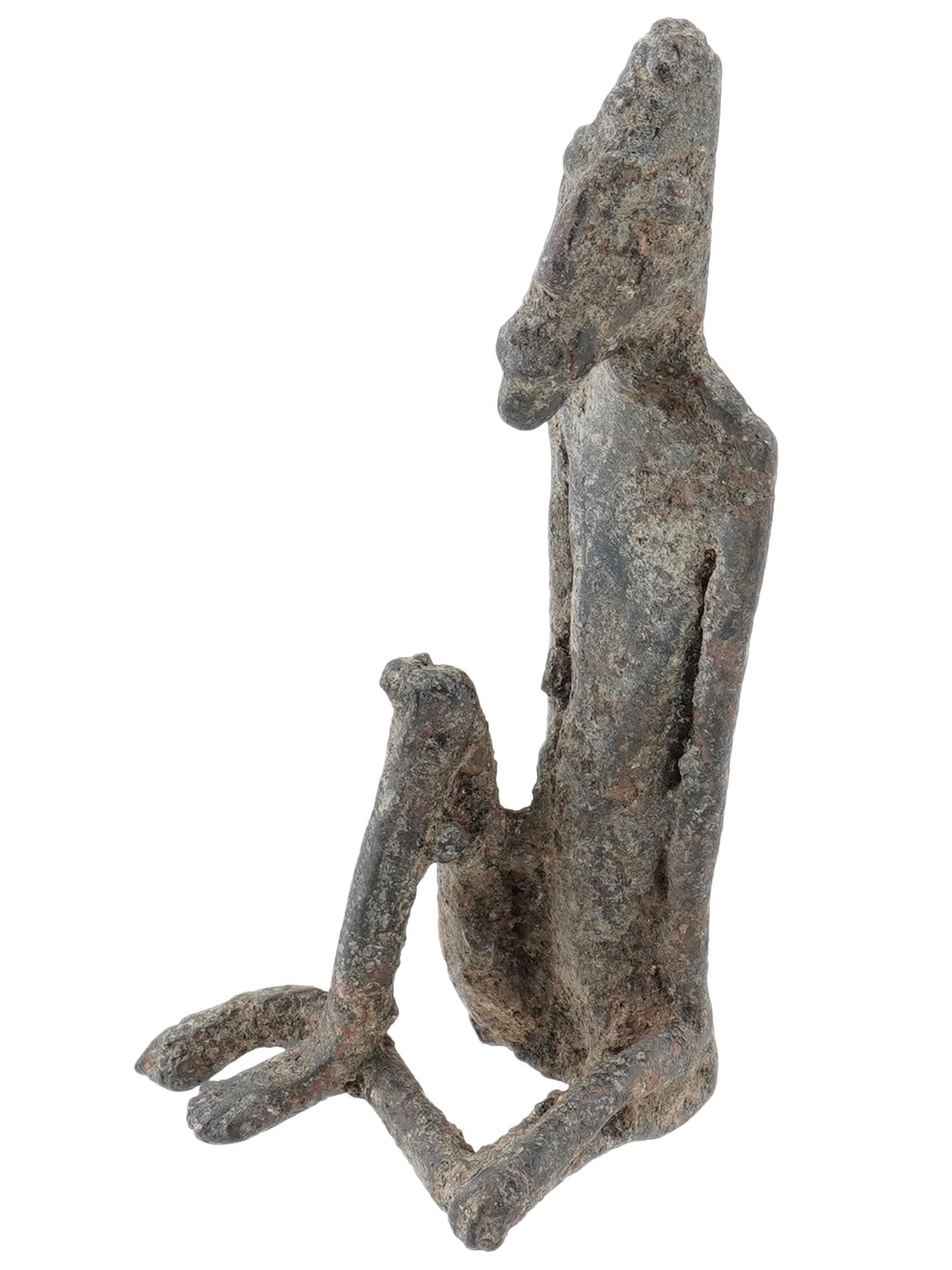 ANTIQUE DOGON BRONZE NUDE FIGURE 1800 AD: An antique Dogon bronze nude figure, circa the 1800 AD. The figure is depicted sitting with elongated limbs and stylized features reflecting the artistic and cultural traditions of the Dogon people. A