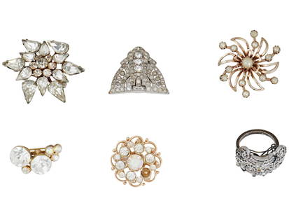 ASSORTMENT OF SIX PIECES OF BROOCHES AND JEWELRY: An assortment of six pieces of jewelry. The lot mostly includes brooches that feature a variety of floral designs comprised of clear, multifaceted stones. One piece is a ring with rhinestones and clea