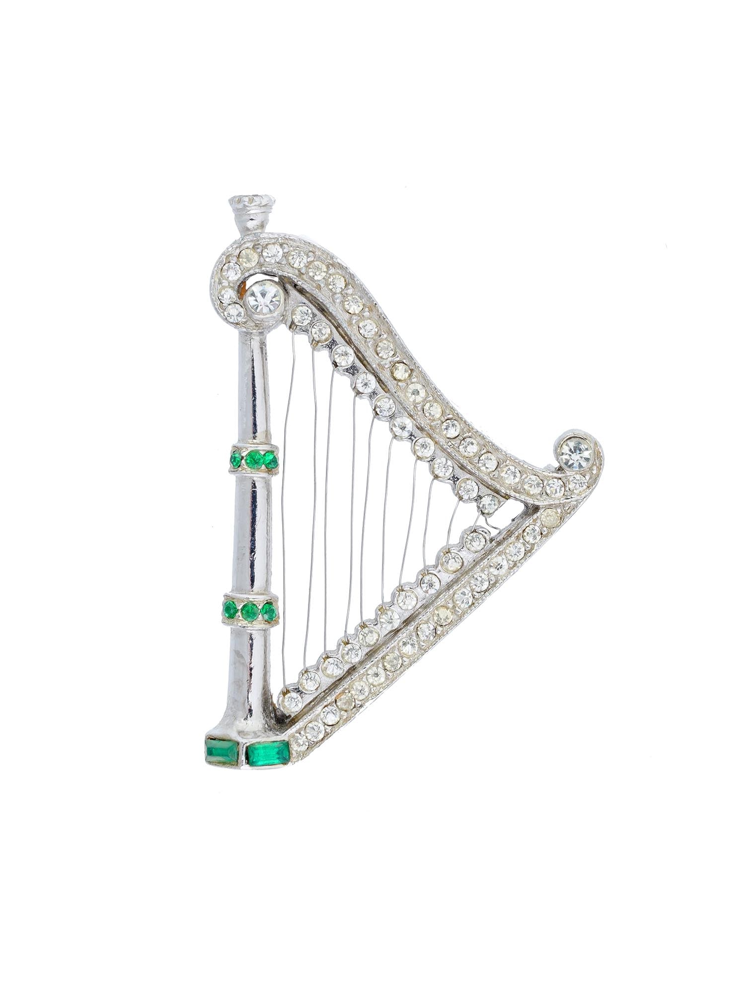 VINTAGE HARP DESIGN FIGURAL COSTUME JEWELRY BROOCH: A vintage figural costume jewelry pin brooch. The brooch is made in a harp design, and encrusted with rhine stones and faux green stones. Unmarked. Vintage and Mid century Ladies Jewelry Wares and Acc