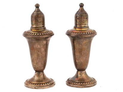 WEIGHTED STERLING SILVER SALT AND PEPPER SHAKERS: A pair of mid 20th century weighted sterling silver salt and pepper shakers. The set with embossed ornamental decoration on the rims has Sterling Weighted Duchin Creation hallmark on the bottom. Each