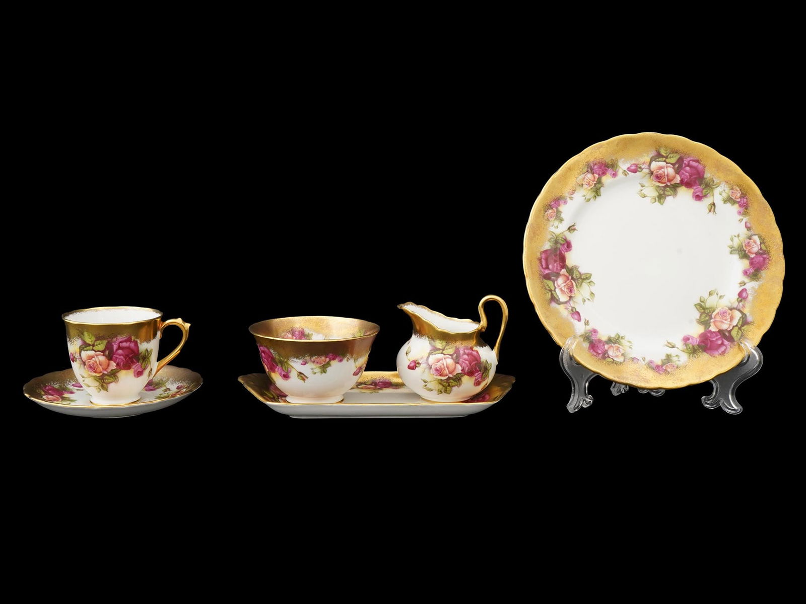 ENGLISH ROYAL CHELSEA GOLDEN ROSE PORCELAIN SET: An English Royal Chelsea Bone China porcelain set adroned with the Golden Rose pattern. The set includes a teacup with a saucer, a sugar bowl with an oblong dish, a creamer, and a plate. All the piece