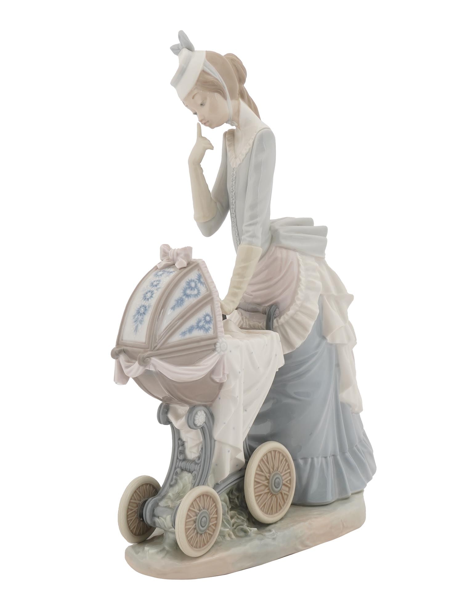 LLADRO DAISA PORCELAIN FIGURINE OF BABY CARRIAGE: A hand-painted porcelain figurine by Lladro, a Spanish porcelain manufacture. The figurine represents a young woman with a baby carriage, 19th-century style. Pastel blue and pink color palette. Titled