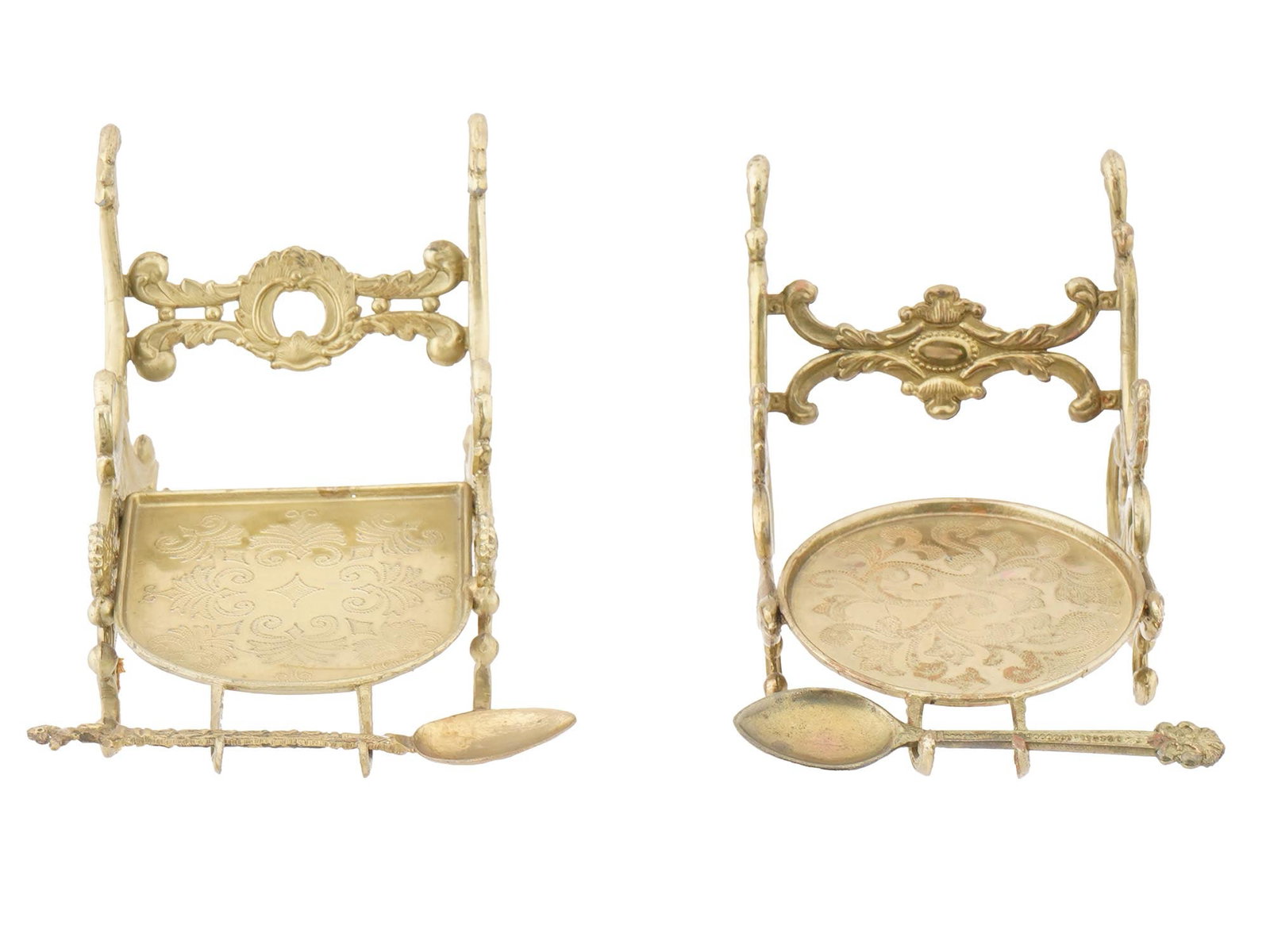 PAIR OF ORNATE BRASS CUP HOLDERS WITH SPOONS: A pair of ornate brass cup holders with spoons. The cup holders have decorative designs and intricate metalwork. One holder features a half round base with a central, engraved design, while the other 