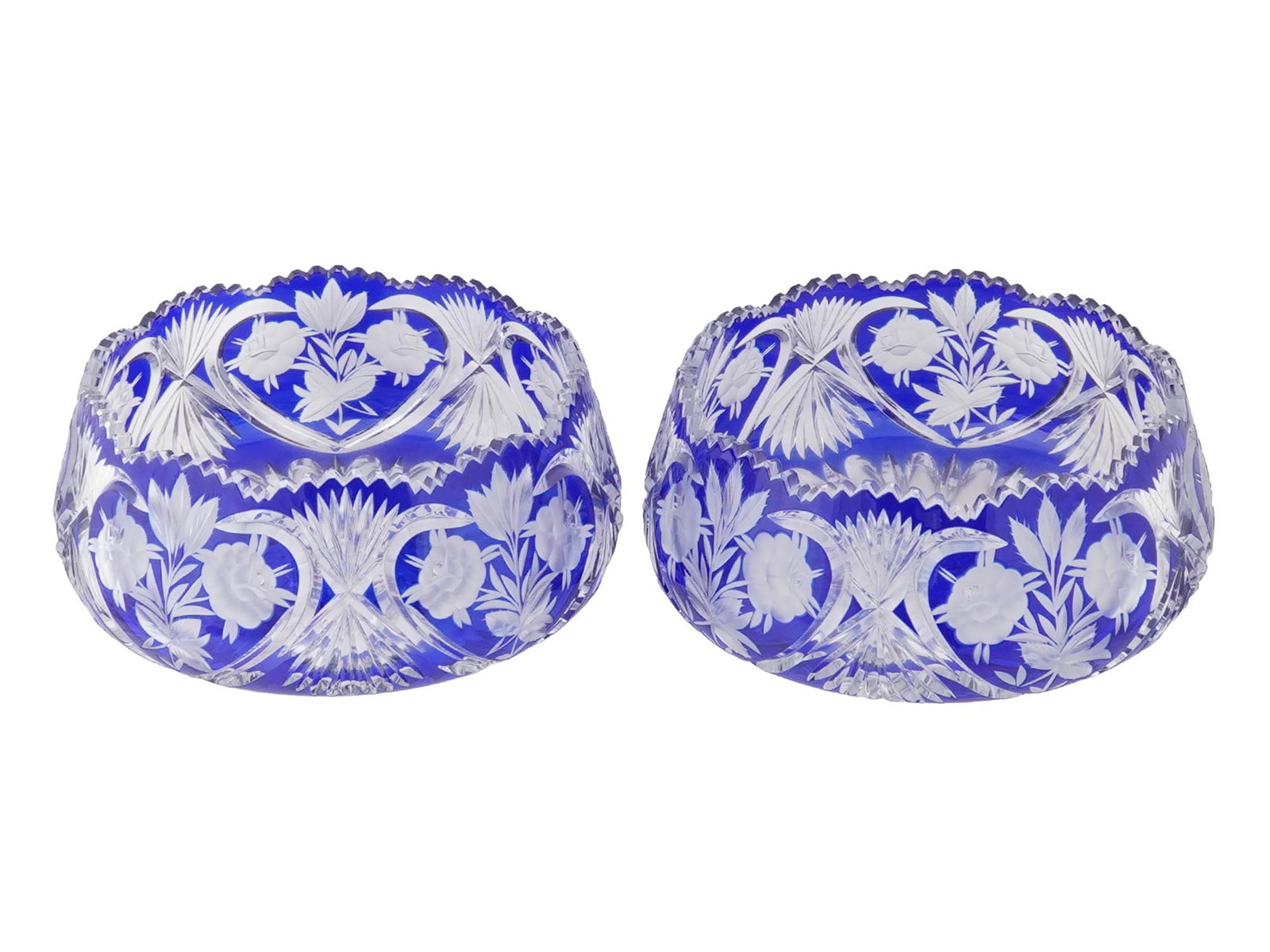 VINTAGE BOHEMIAN COBALT BLUE CRYSTAL GLASS ROSE BOWLS: A pair of vintage Bohemian rose bowls, crafted in richly colored cobalt blue cut to clear crystal. Each bowl features intricate deep-cut floral and foliate motifs and is finished with an elegant sawto