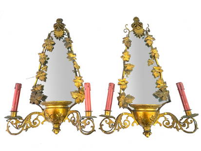 ANTIQUE GILT BRASS MIRRORED ELECTRICAL WALL SCONCES: A pair of identical early 20th-century gilt brass girandole mirrors with modern electrical fittings. Triangular mirror with wooden backing. Acanthus and grape leaves framing, relief baluster base conc