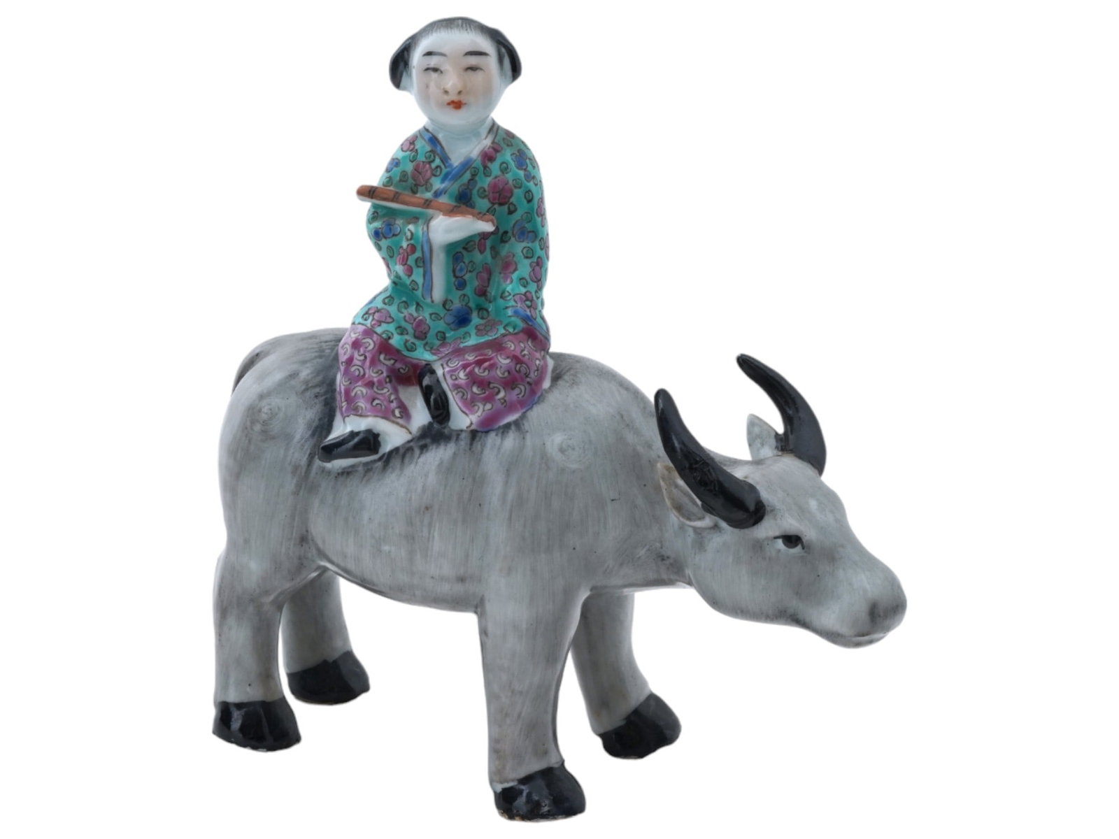 CHINESE PORCELAIN FIGURINE HERDBOY RIDING BUFFALO: A vintage Chinese porcelain figurine depicting a herdboy riding a water buffalo. The boy is depicted with a traditional Chinese childrens hairstyle, holding a flute in his hand, and wearing green and 