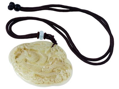 ANTIQUE CHINESE CARVED JADE DRAGON AMULET PENDANT: An antique Chinese late Qing Dynasty figural amulet pendant hand carved of pale green jade, most likely Hotan or Hetian. The pendant depicts a fragon among swirled clouds engraved with detailed patter