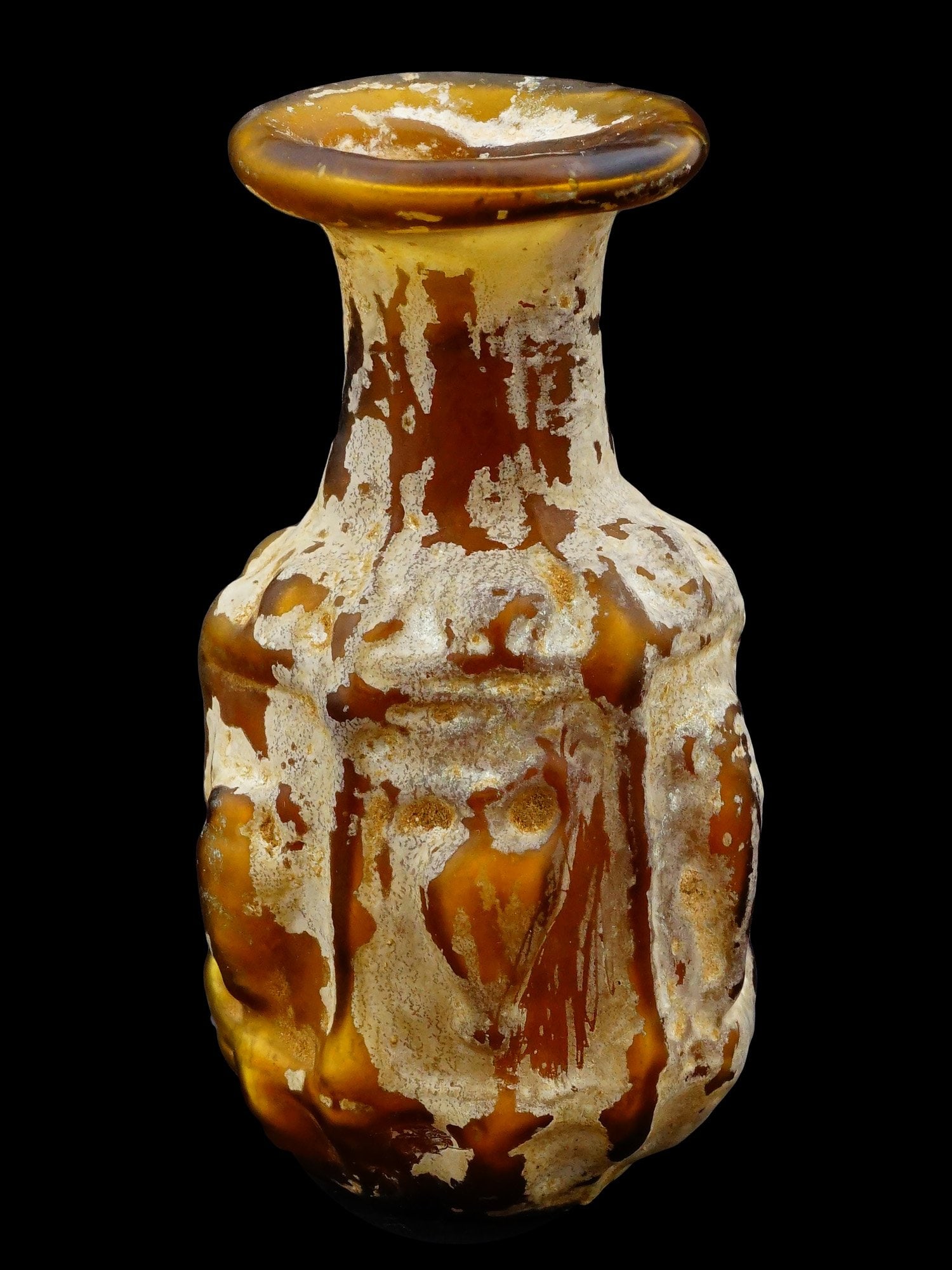 ANCIENT ROMAN BLOWN GLASS BOTTLE WITH AMPHORA MOTIFS: An ancient Roman mold?blown glass bottle with amphora motifs, featuring a globular body divided into decorative panels, each adorned with a raised amphora design. The shoulder is embellished with leaf
