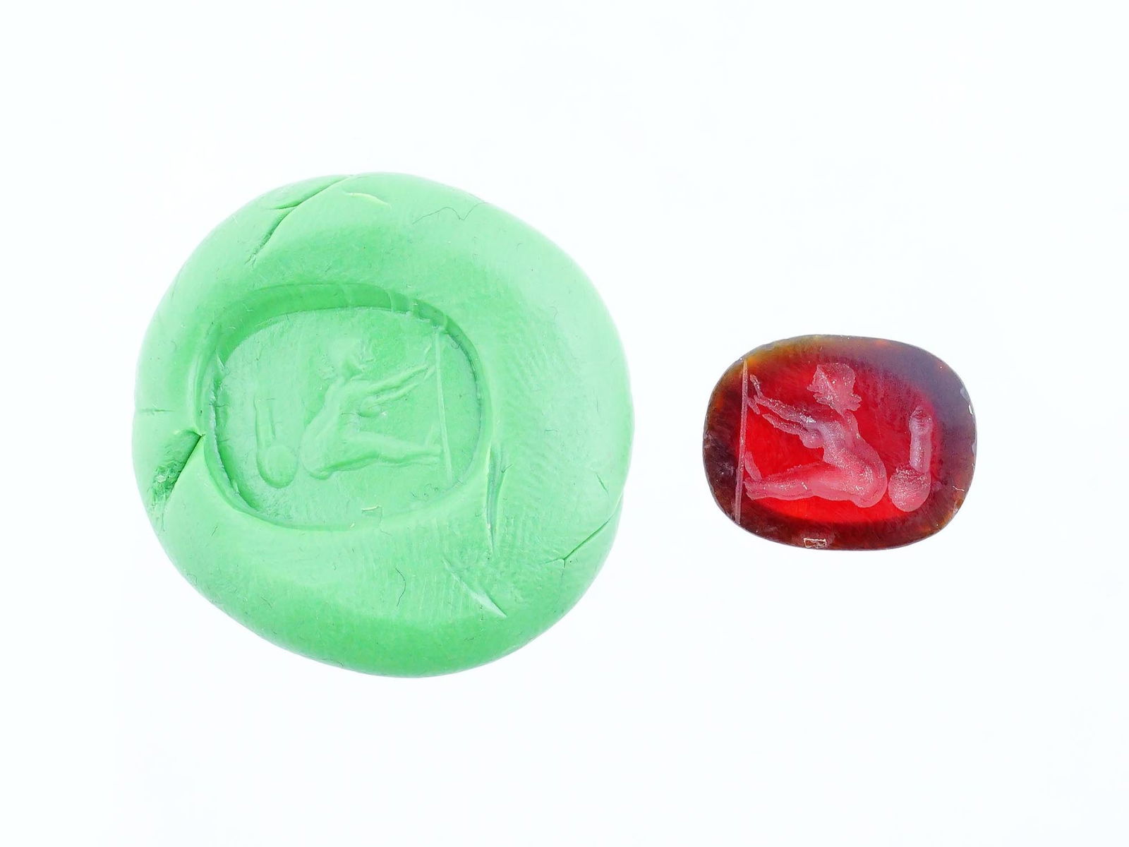 CARVED STONE INTAGLIO ANCIENT ROMAN EROTIC SCENE: A carved carnelian stone intaglio featuring an ancient Roman erotic scene involving a female figure seated next to an erected penis. This detailed engraving reflects the artistic and symbolic traditio