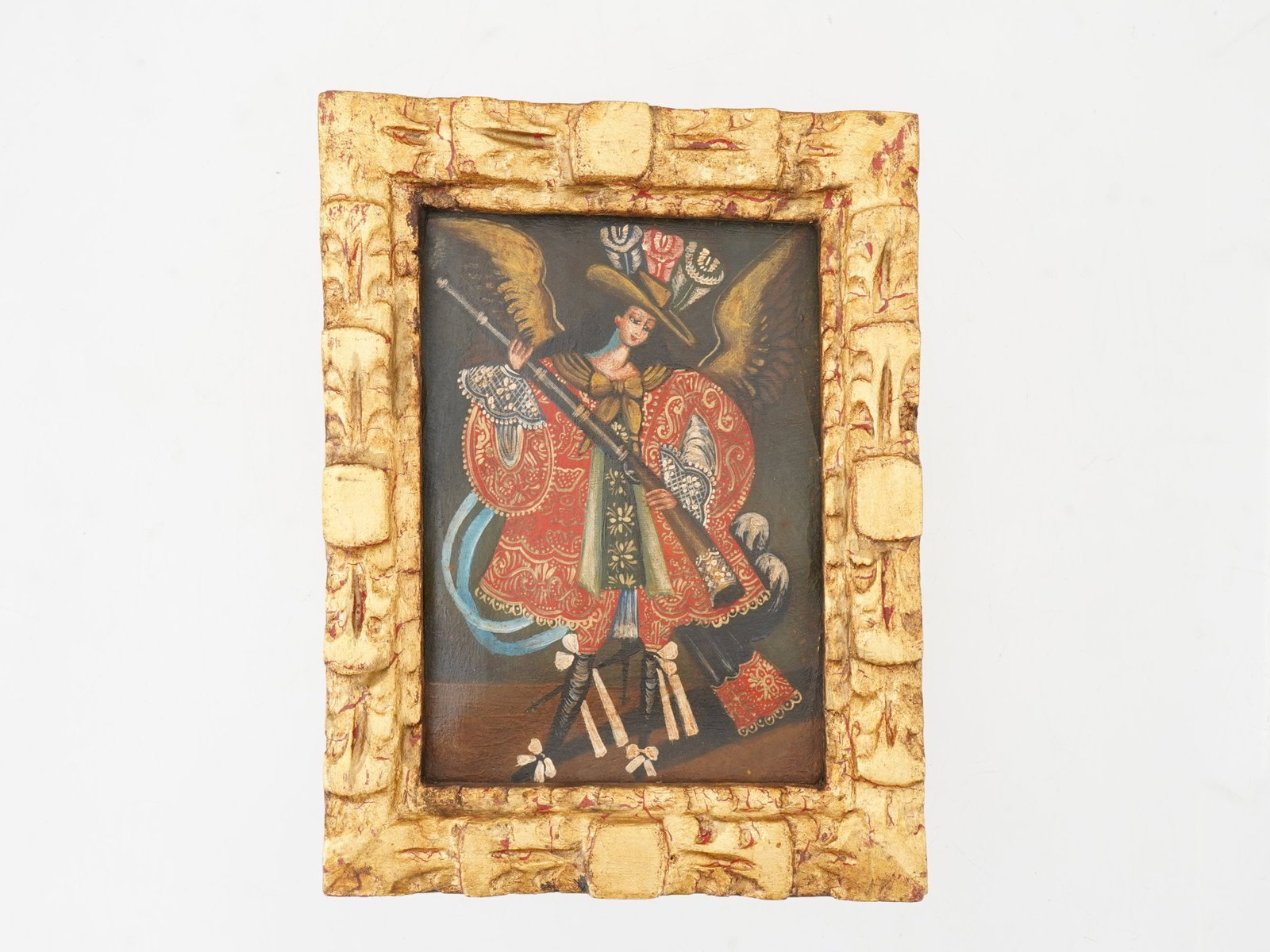 ANTIQUE CUZCO SCHOOL ANGEL ARCABUCERO OIL PAINTING: An antique Cusco School oil painting on canvas depicting a religious portrait of an angel holding a gun and wearing a plumed hat. Completed with gilt accents. Framed. Antique South American Religious 
