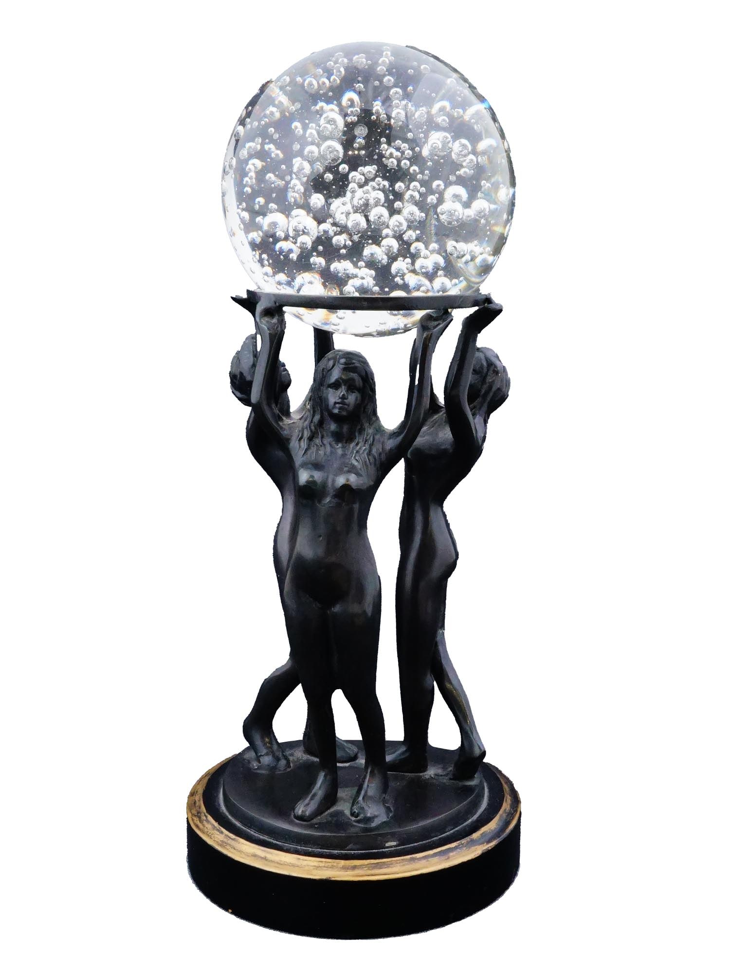 FEMALE FIGURES BALL BRONZE SCULPTURAL PAPERWEIGHT: A vintage black patinated bronze sculptural paperweight. The ware features three female nude figures dancing together while gracefully supporting a shimmering crystal ball overhead. The sculpture is s