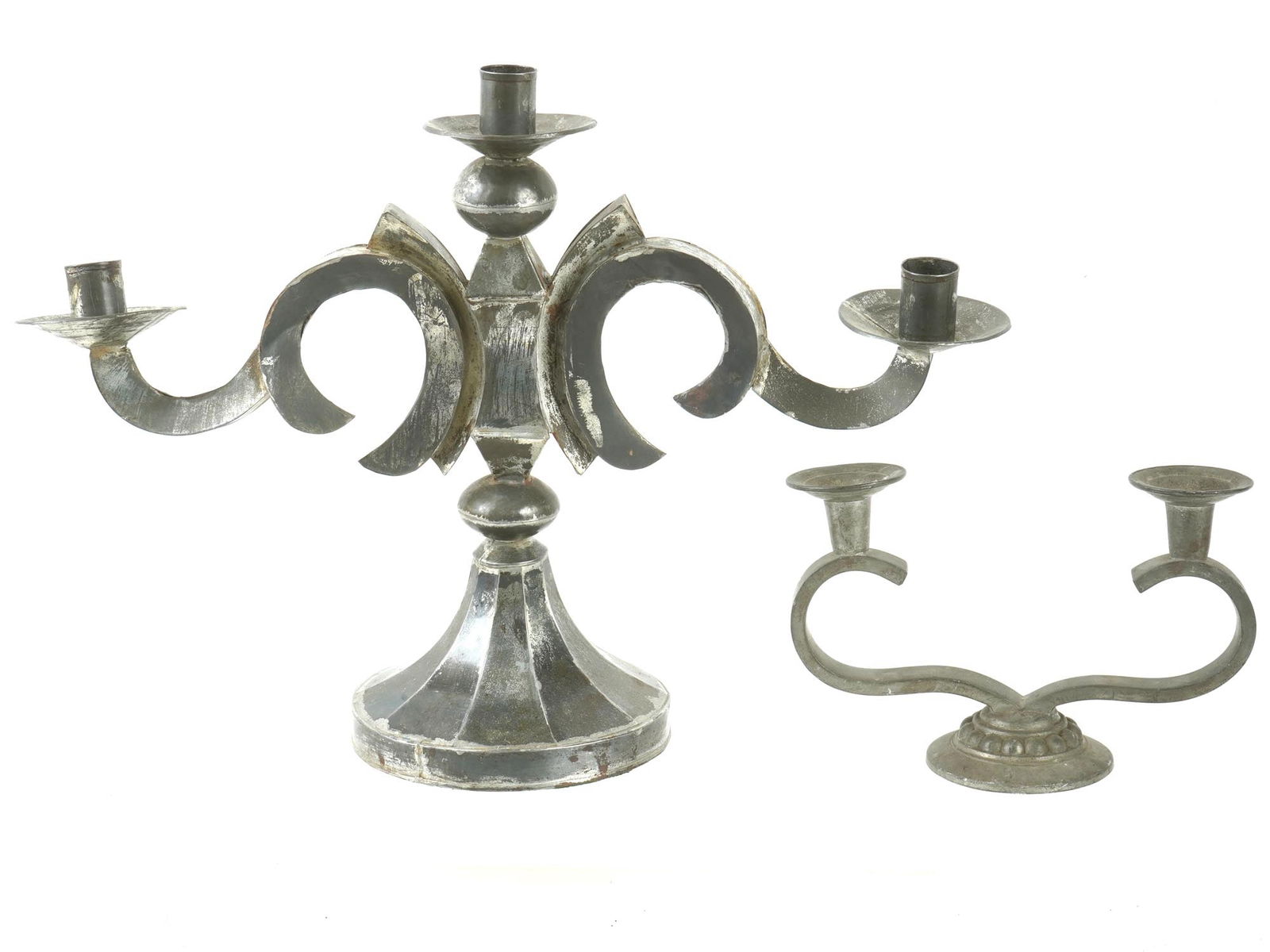PAIR OF TIN AND METAL CANDELABRAS: A pair of tin and metal candelabras showcasing ornate scrollwork. The larger candelabra, made of polished metal with a robust base, features a unique three arm structure, ideal for holding multiple ca