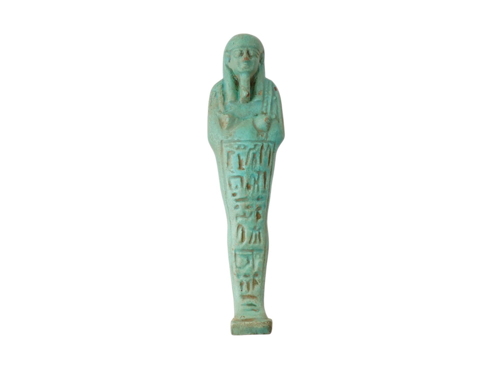 ANCIENT EGYPTIAN 26TH DYNASTY GLAZED FAIENCE USHABTI: An ancient Egyptian green glazed faience Ushabti with arms crossed over the chest, holding a pick and hoe, with a column of ten rows of hieroglyphs running vertically down the front of the body. Circa