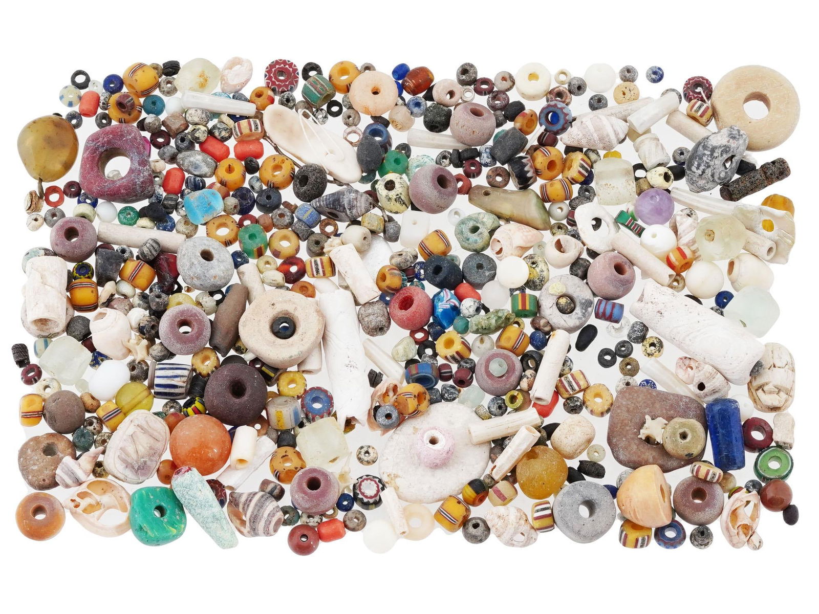 COLLECTION OF ANCIENT MIXED AMYTHEIST GLASS BEADS: A collection of ancient beads. The beads are of various shapes, sizes, and materials, including glass, amethyst, and other stone beads. Many have a circular or tubular form, while others are irregular