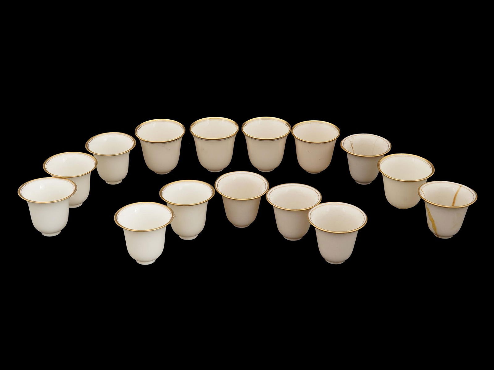 ANTIQUE ANERICAN LENOX DEMITASSE CUP LINER SET: A set of 15 Lenox porcelain demitasse cup liners. Each features a 24k gold rim and smooth exterior. Marked to the bottom with the manufacturer stamp and brand logo. Made in the USA. Circa the 1950s. V