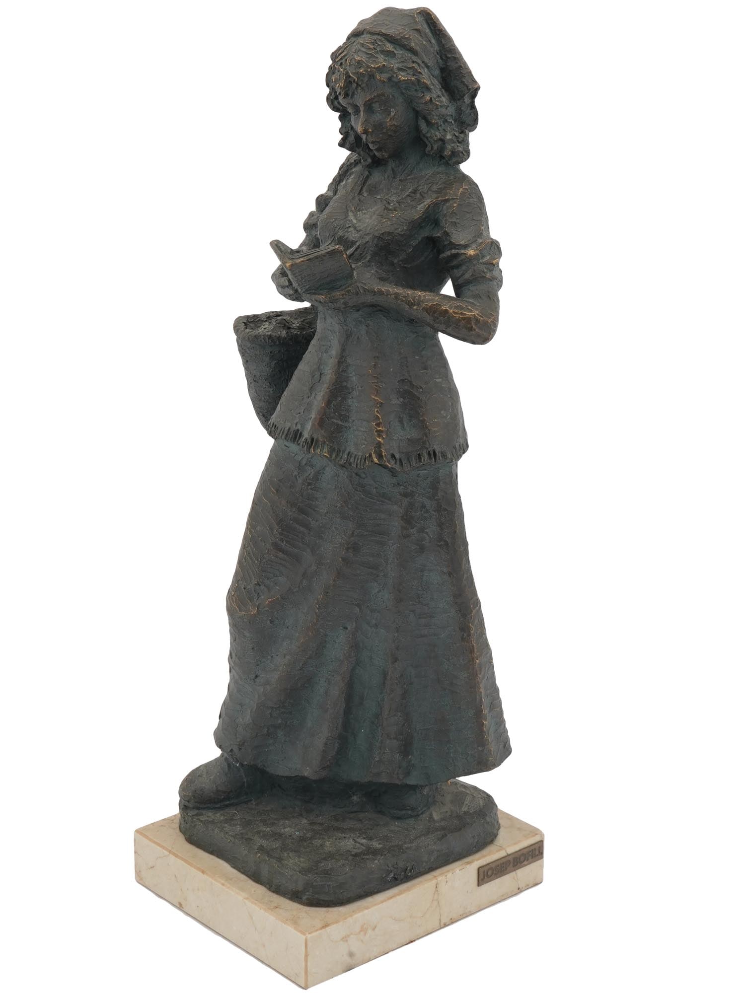 BRONZE FIGURINE OF A GIRL READING BY JOSEP BOFILL: A patinated bronze composite sculpture depicting a figure of a young woman with a basket reading a book. The figurine is mounted on a beige marble base. Numbered 139 on the backside of the scultpure.