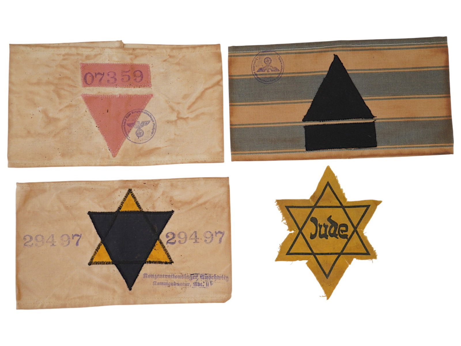 WWII HOLOCAUST CONCENTRATION CAMP ARMBANDS: A lot of three World War II Jewish concentration camp fabric armbands. Embroidered triangles and Auschwitz stamps, one armband is striped. Homosexual, Asocial, Jewish Asocial. The lot also includes a