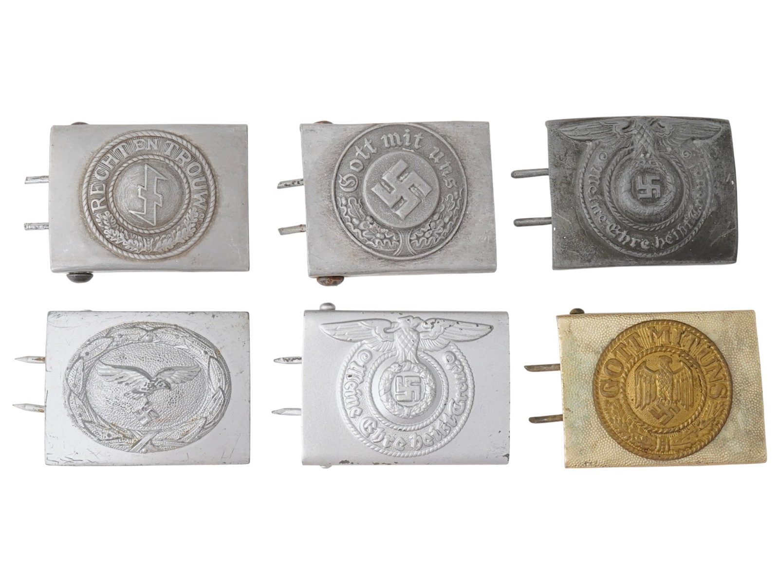 GERMAN DUTCH WWII BELT BUCKLES IN SILVER AND GOLD TONES: A group of six German and Dutch WWII type belt buckles in silver and gold tones. The buckles feature Nazi symbols, including the eagle, swastika, and oak leaf wreaths. Most of the buckles bear the Ger