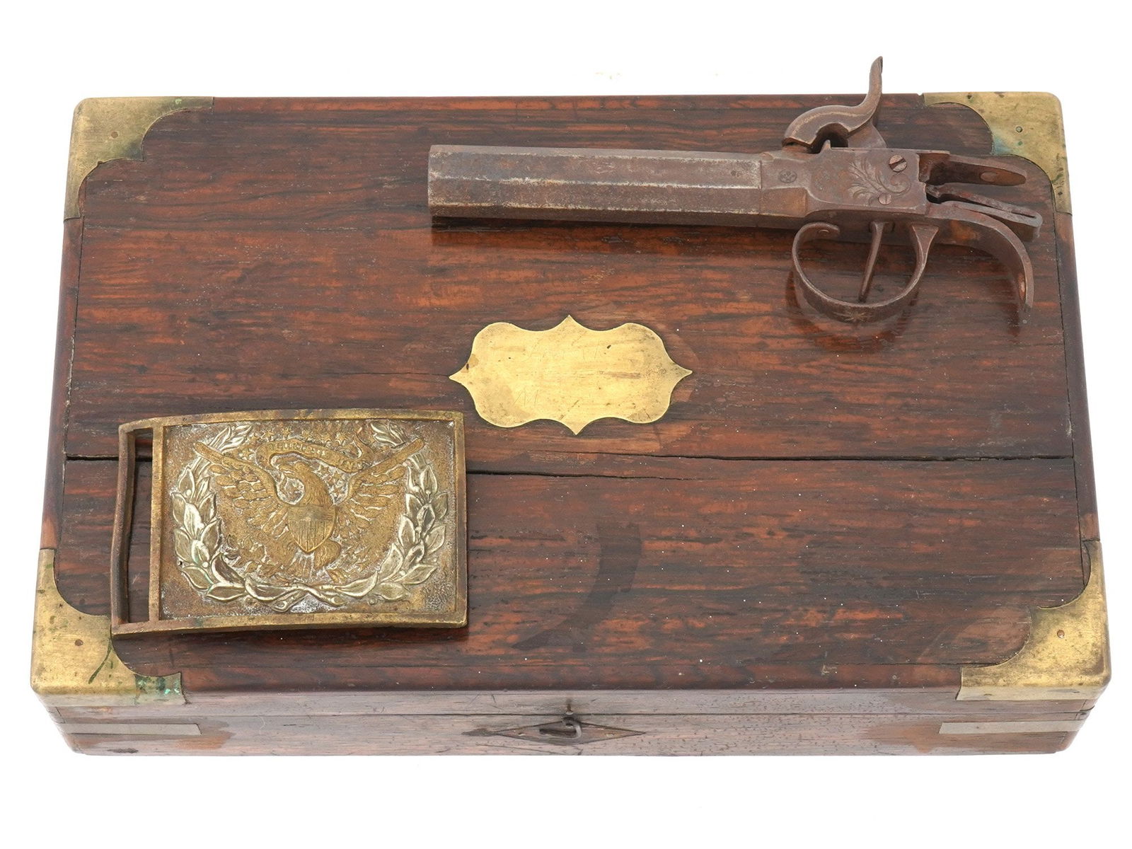 LOT OF CIVIL WAR WOOD BOX PISTOL AND METAL BUCKLE: A collection of three American Civil War wares. The collection includes a box constructed from hardwood with brass fittings on the corners; a pistol featuring classic design elements, engraved with a