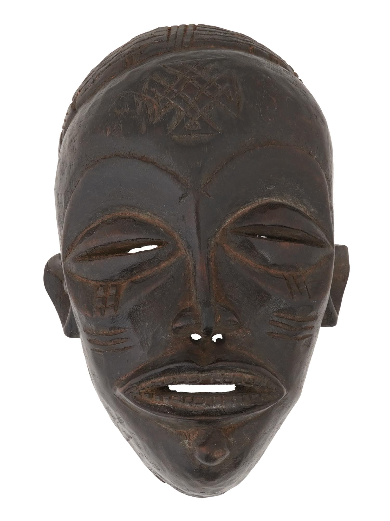 SMALL CENTRAL AFRICAN CHOKWE PEOPLE CARVED MASK: A small Central African hand carved wooden mask of the Chokwe people from Congo and Angola. The mask depicts an elongated face with narrow eyes and an open mouth with teeth. It is decorated with ethni