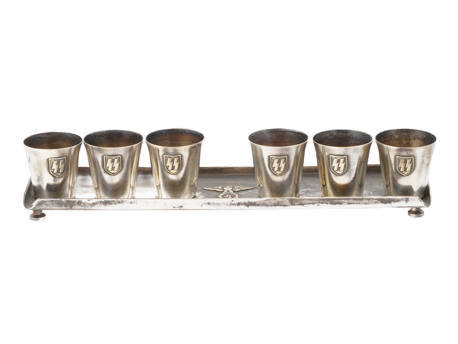 SET OF SIX WWII NAZI GERMAN SS SCHNAPPS CUPS WITH STAND: A set of six schnapps cups with a stand, part of a Waffen-SS officers canteen from World War II, comprising seven items in total. The cups feature the SS runes images, while the tray bears the Nazi ea