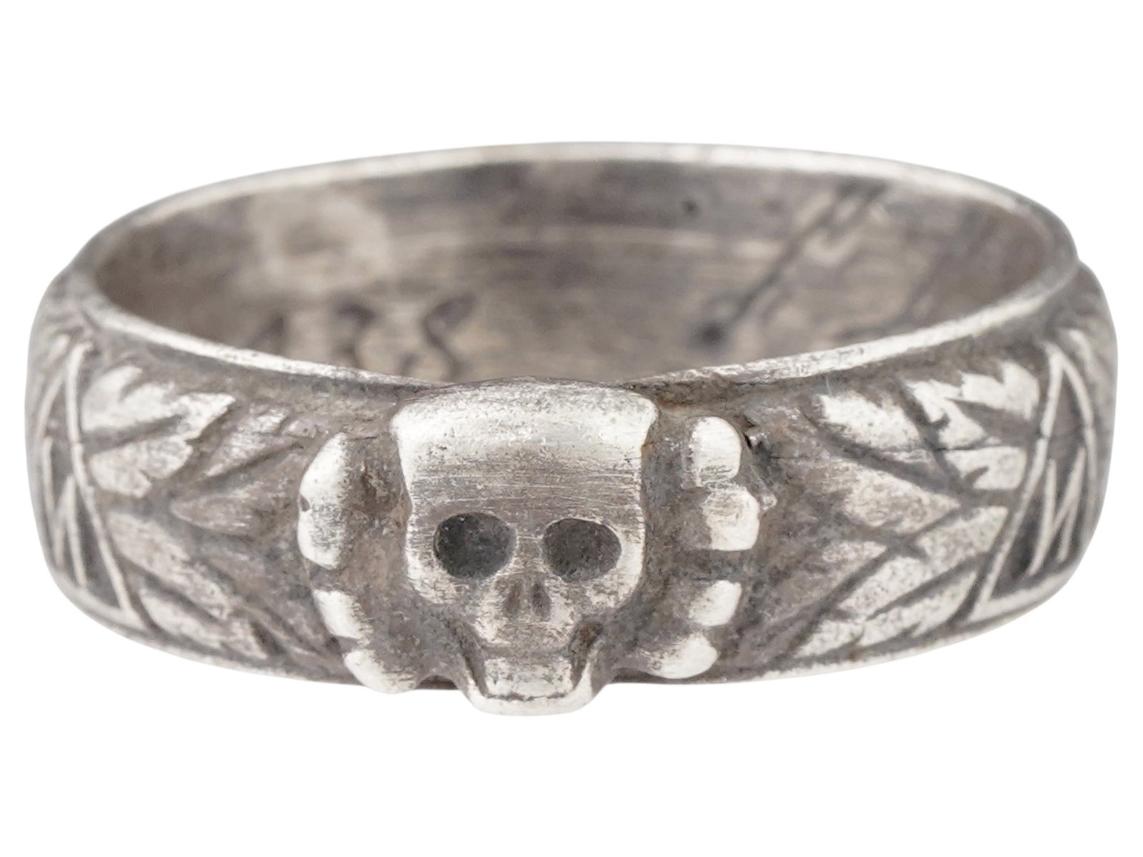 WWII MODEL NAZI GERMAN SS HONOR RING: A World War II model Nazi German insignia, the SS Honor ring, also known as the SS-Ehrenring or Totenkopfring. The piece bears an embossed scull with bones, as well as five Armanen runes. The name of 