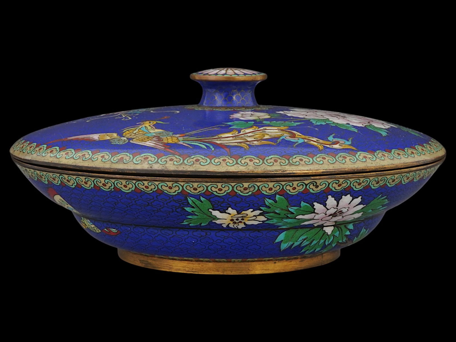 CHINESE CLOISONNE ENAMEL LIDDED POT: A Chinese cloisonne enamel lidded pot. The lid is adorned with vibrant phoenix, dragon and peony designs. The exterior of the pot is adorned with a butterfly and peony designs, accented with repeating