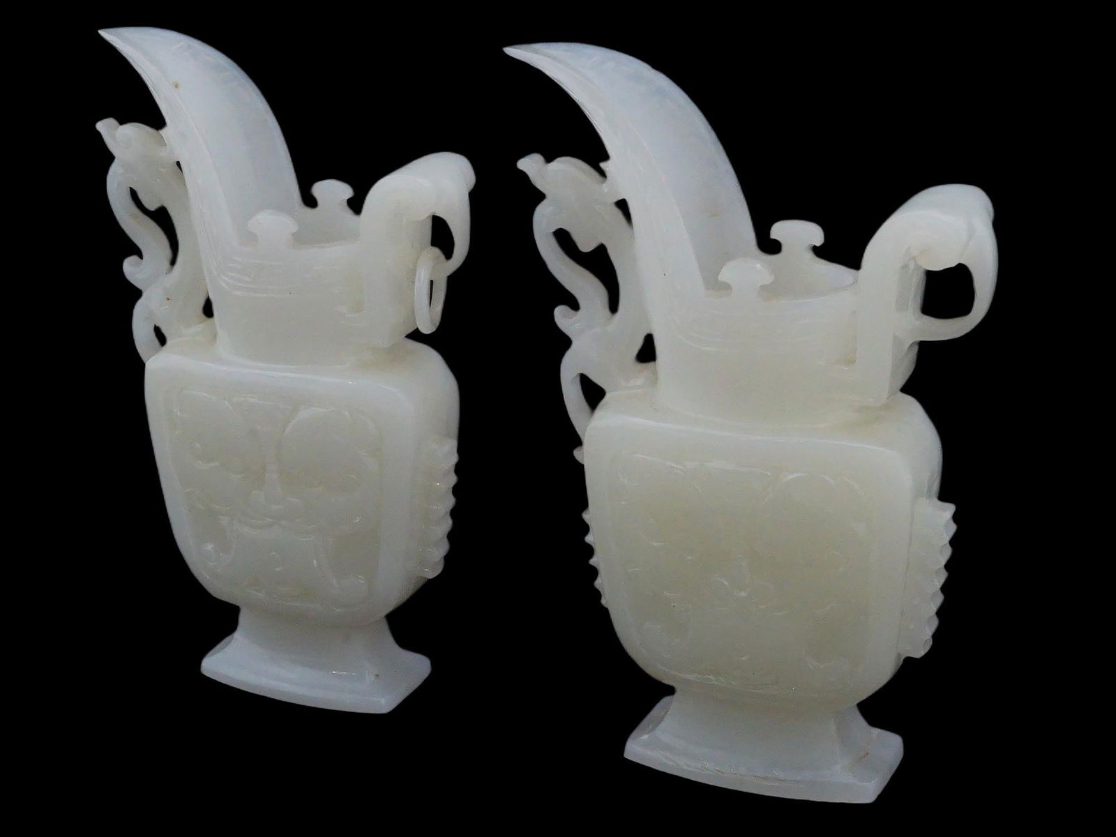 PAIR OF CHINESE CARVED WHITE JADE WINE VESSELS: A pair of Chinese carved white Jade wine vessels. Each ornamental vessel is adorned with distinctive vein, side flattened body not hollowed out, decoration on both sides with lion mask in Taotie style