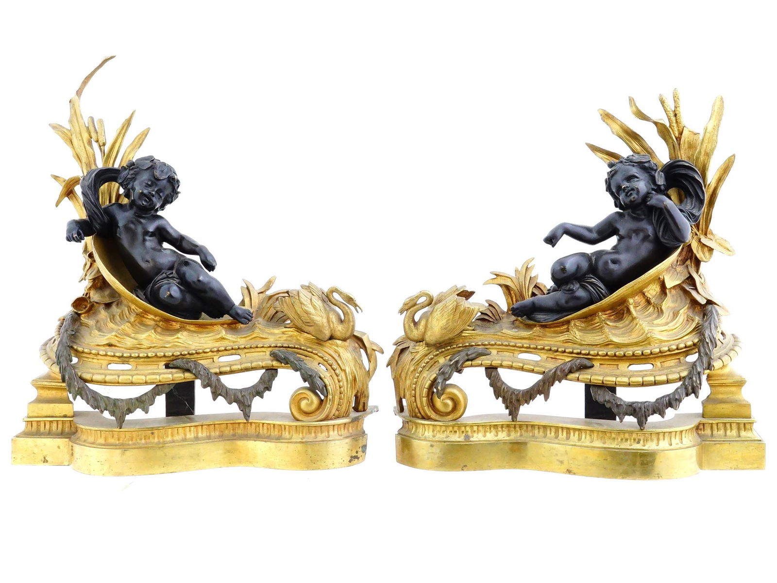 ANTIQUE FRENCH GILT BRONZE FIGURAL CHERUB ANDIRONS: A pair of antique French gilt bronze figural andirons, crafted and depicting reclining cherubs accompanied by swans, set amidst cattails. The figures rest on elegant scroll-form bases. Dates to the la