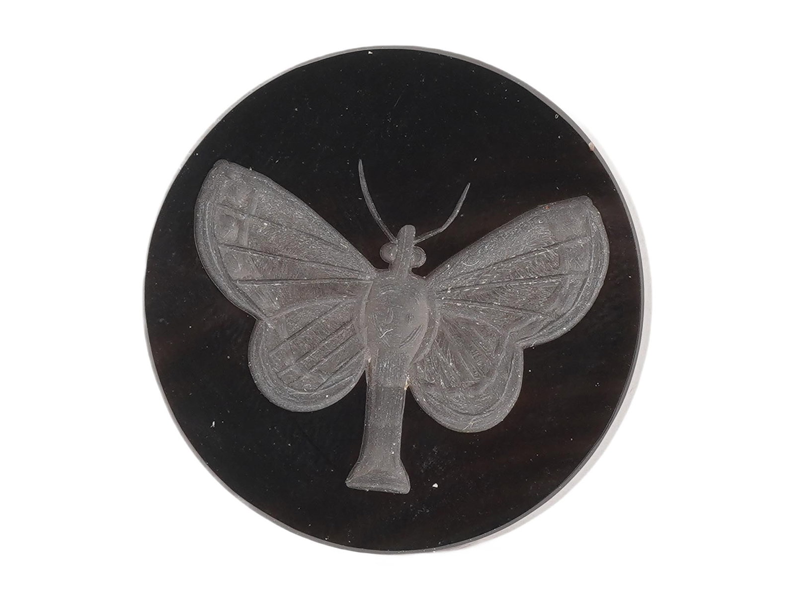 BLACK INTAGLIO CARVING BUTTERFLY OR MOTH: A black intaglio carving depicting a butterfly or moth, likely crafted from onyx, hematite, or dark glass. It may have functioned as a seal, signet ring, fob, or even a decorative paperweight. Gemston