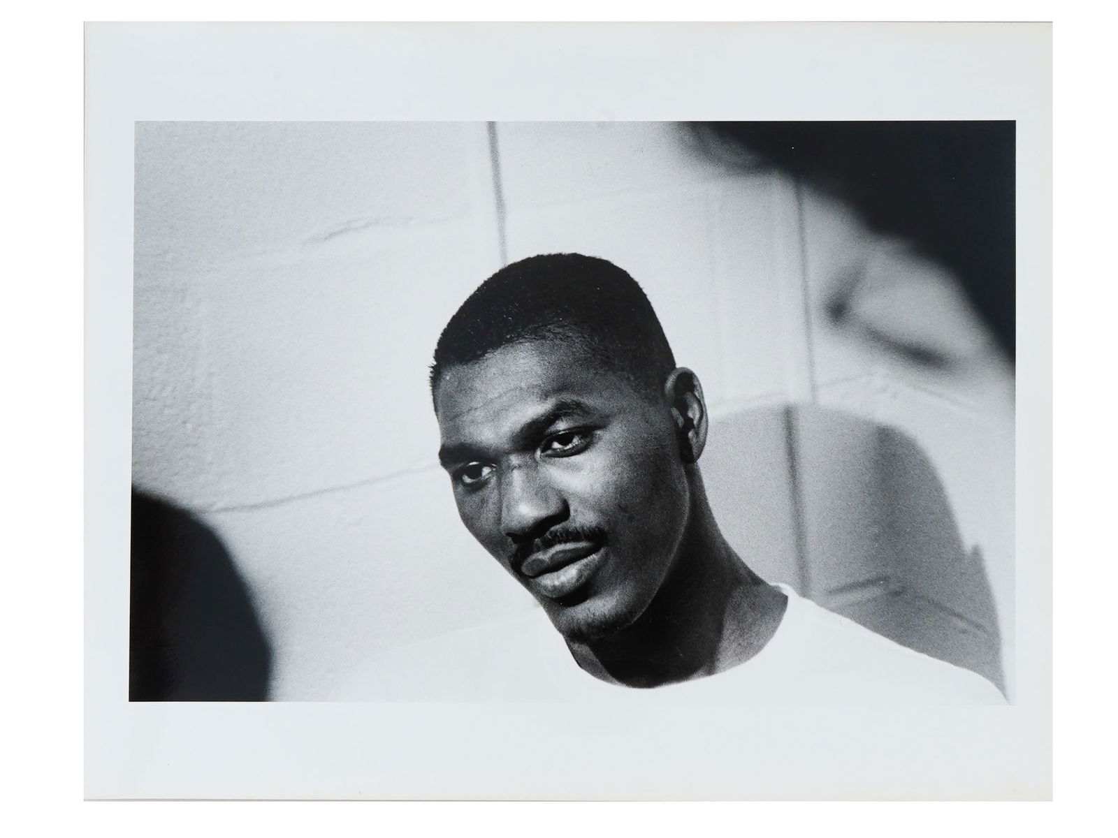 VTG 1994 BLACK AND WHITE PHOTO OF HAKEEM OLAJUWON: A vintage black and white photo of Hakeem Abdul Olajuwon. Bears a paper label with information about the photo. Titled, Nigerian born All-Star National Basketball Association player with the Houston R