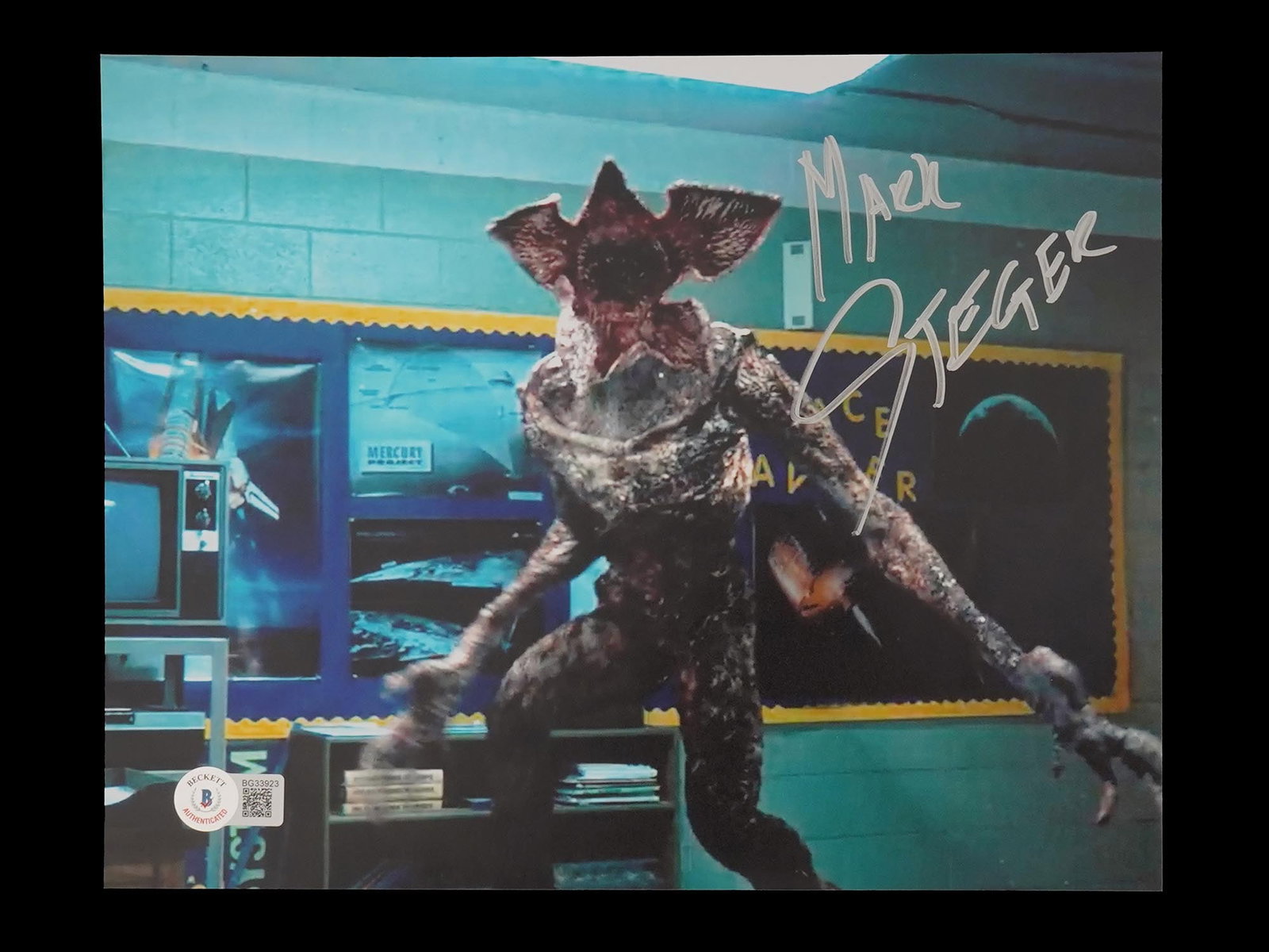 STRANGER THINGS SERIES PHOTO SIGNED AUTHENTICATED: A color photograph depicting a scene from the Stranger Things series. Signed by Mark Steger, born 1962, an American actor, performance artist, and choreographer. He portrays the Demogorgon in season o