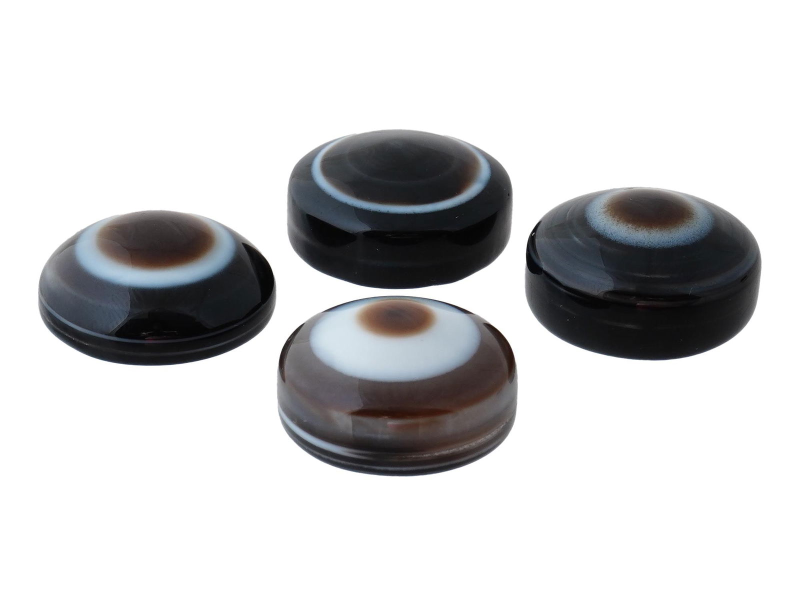 COLLECTION OF FOUR POLISHED EYE AGATE JEWELRY PENDANTS: A collection of four polished eye agate pendants, each hand-carved to enhance the natural concentric banding and eye formations characteristic of this gemstone. The stones display a range of earthy to