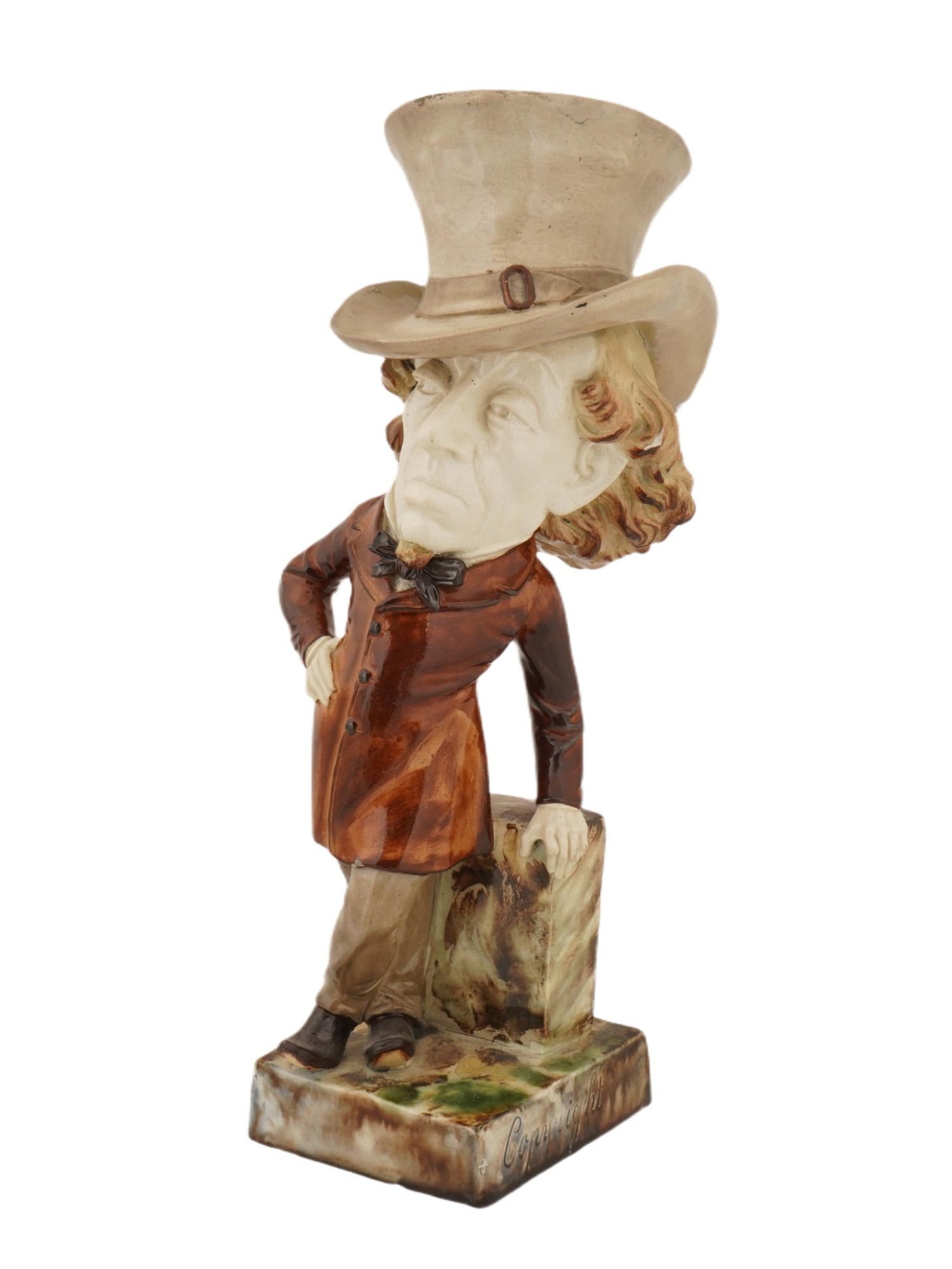 WHITMAN AND ROTH STAFFORDSHIRE MAJOLICA DISRAELI FIGURE: A Whitman and Roth, Staffordshire majolica caricature figure of Benjamin Disraeli, modelled standing beside a plinth. Marked on the base and the bottom. Disraeli is shown standing with his left hand o