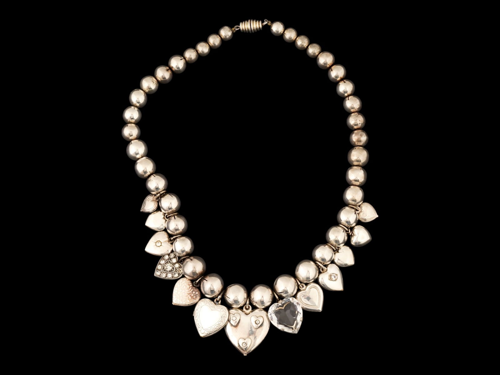 VINTAGE STERLING SILVER PUFFY HEART BALL NECKLACE: A vintage sterling silver puffy heart ball necklace, featuring a beaded silver chain adorned with multiple dangling heart-shaped charms and small heart lockets. Vintage Necklaces And Jewelry Collectib