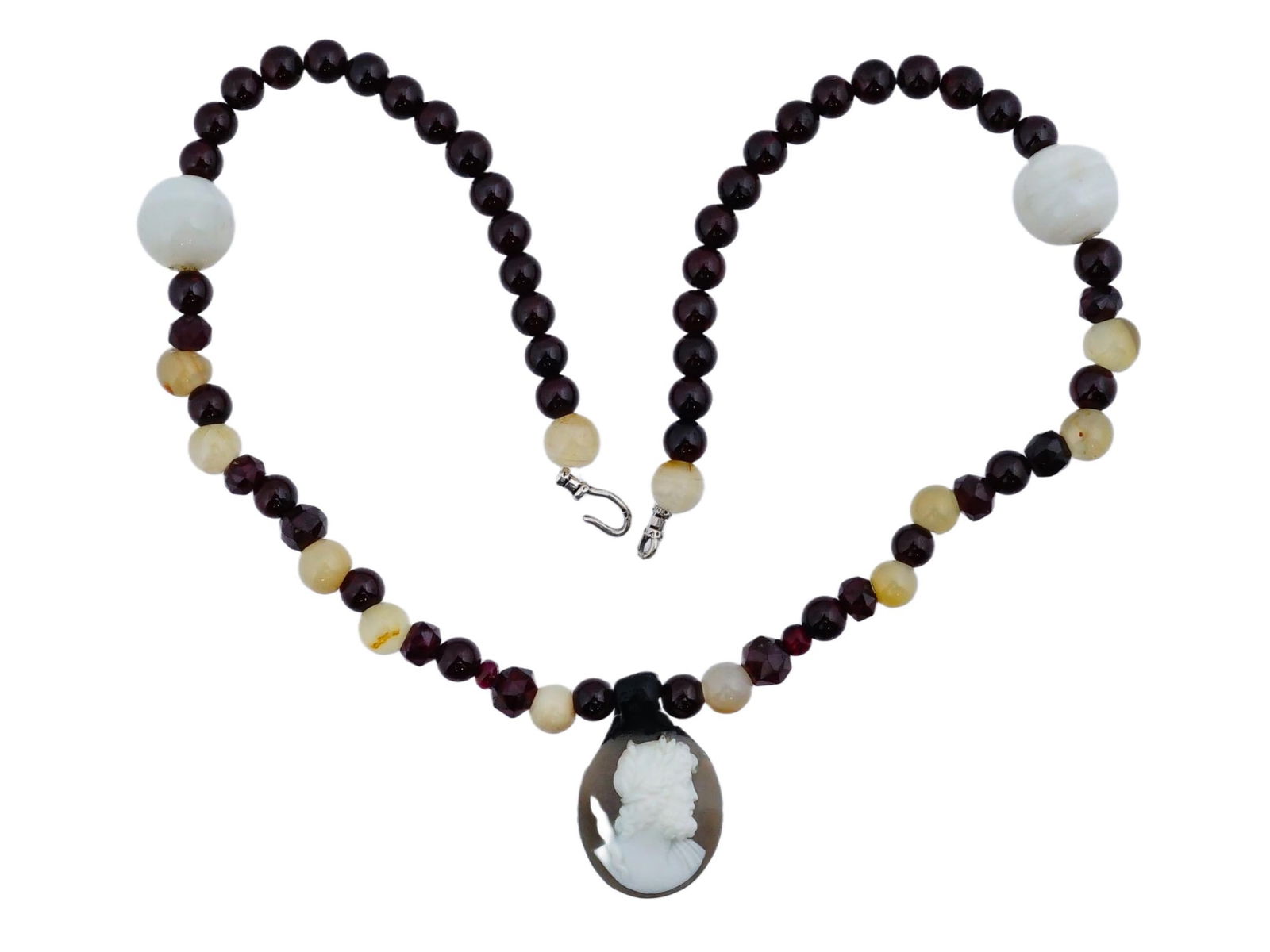 VINTAGE BEADED GEMSTONE NECKLACE WITH A CAMEO PENDANT: A vintage beaded gemstone necklace with a cameo pendant, composed of faceted deep red garnet beads, rounded yellow beads, and large smooth white beads. The focal point is an oval cameo pendant, featur