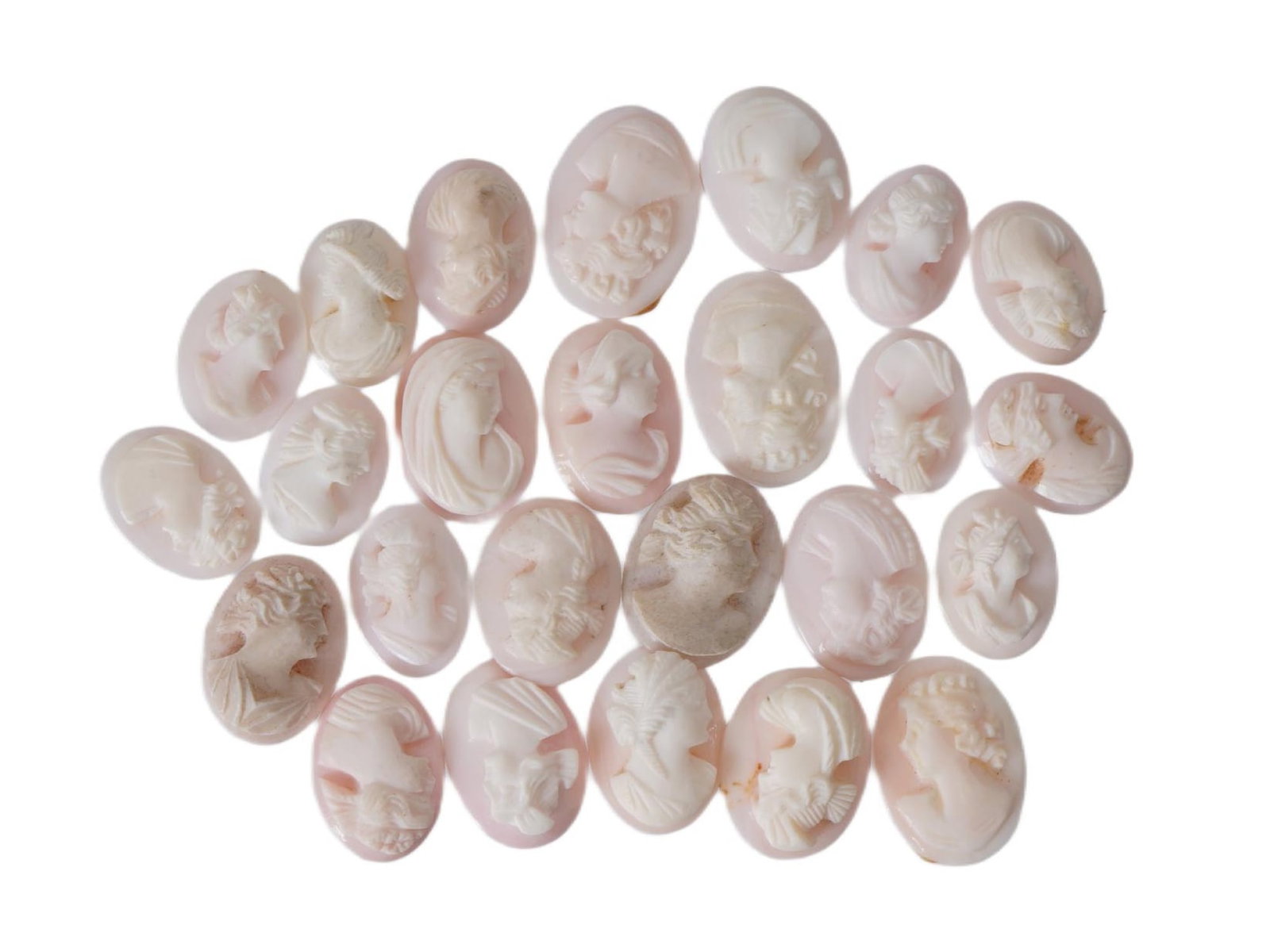 COLLECTION OF FEMALE PORTRAIT CARVED CORAL CAMEOS: A collection of hand carved pink coral cameos. A total of 15 items. Each piece depicts a female profile portrait rendered in high relief. Oval shape. Collectible Jewelry And Glyptic Art, Sculpture.