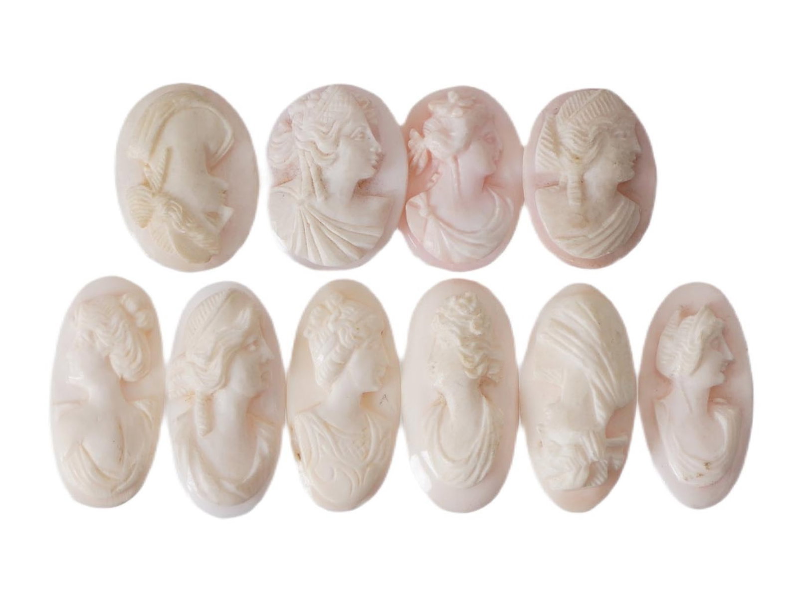 COLLECTION OF FEMALE PORTRAIT CARVED CORAL CAMEOS: A collection of hand carved pink coral cameos. A total of 10 items. Each piece depicts a female profile portrait rendered in high relief. Oval shape. Collectible Jewelry And Glyptic Art, Sculpture.