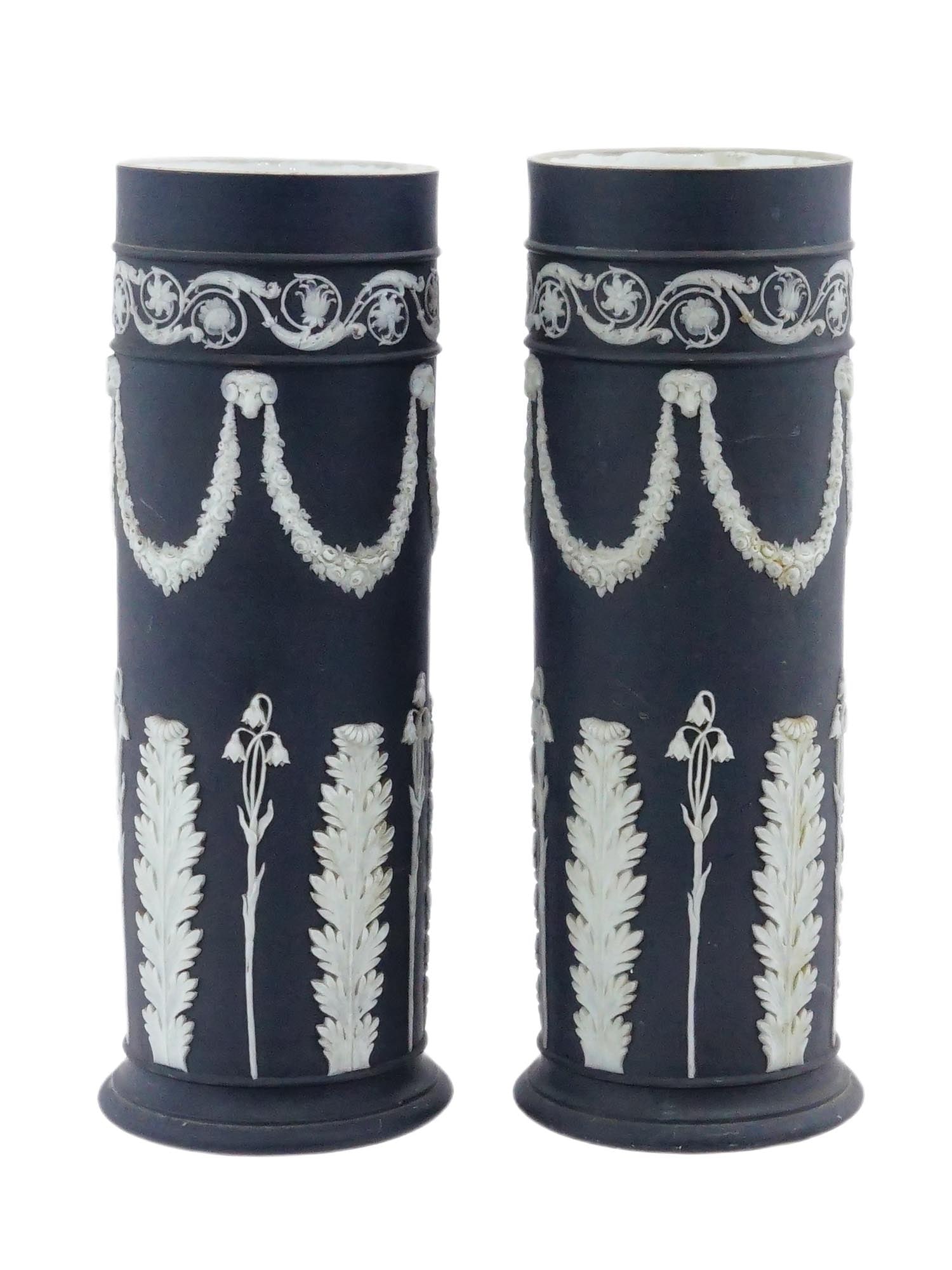 ENGLISH WEDGWOOD JASPERWARE BLACK BASALT SPILL VASES: A pair of vintage English Wedgwood jasperware black basalt spill vases. Cylindrical vases decorated with neoclassical relief appliques in white jasper porcelain with motifs of garlands and acanthus le