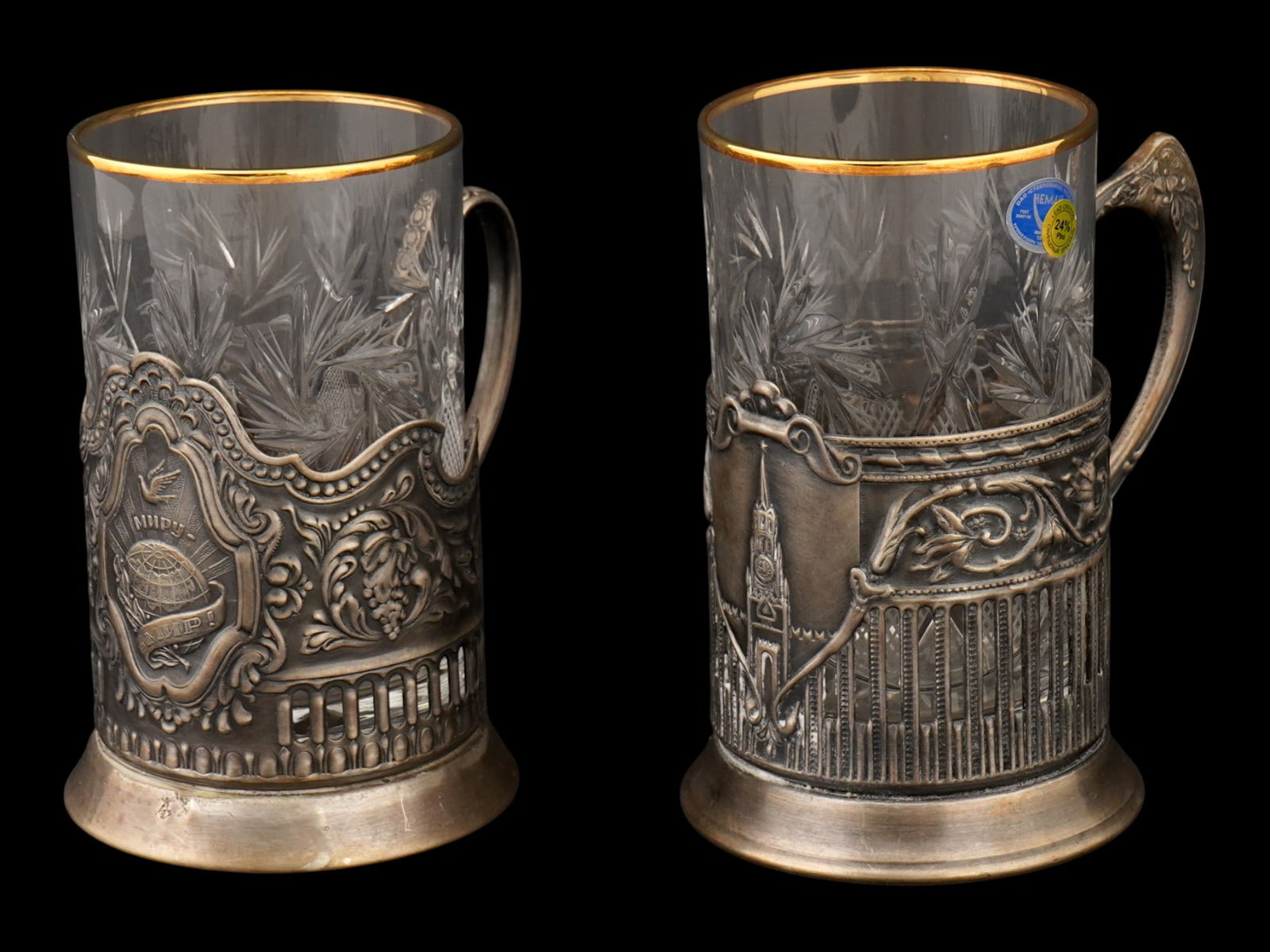 PAIR OF RUSSIAN COPPER TEA GLASS HOLDERS WITH CUPS: A pair of Russian Soviet era copper handled tea glass holders or podstakanniks. Ca. 1960s. Embossed decor, the first holder depicts the Spasskaya tower of the Moscow Kremlin, the second holder feature