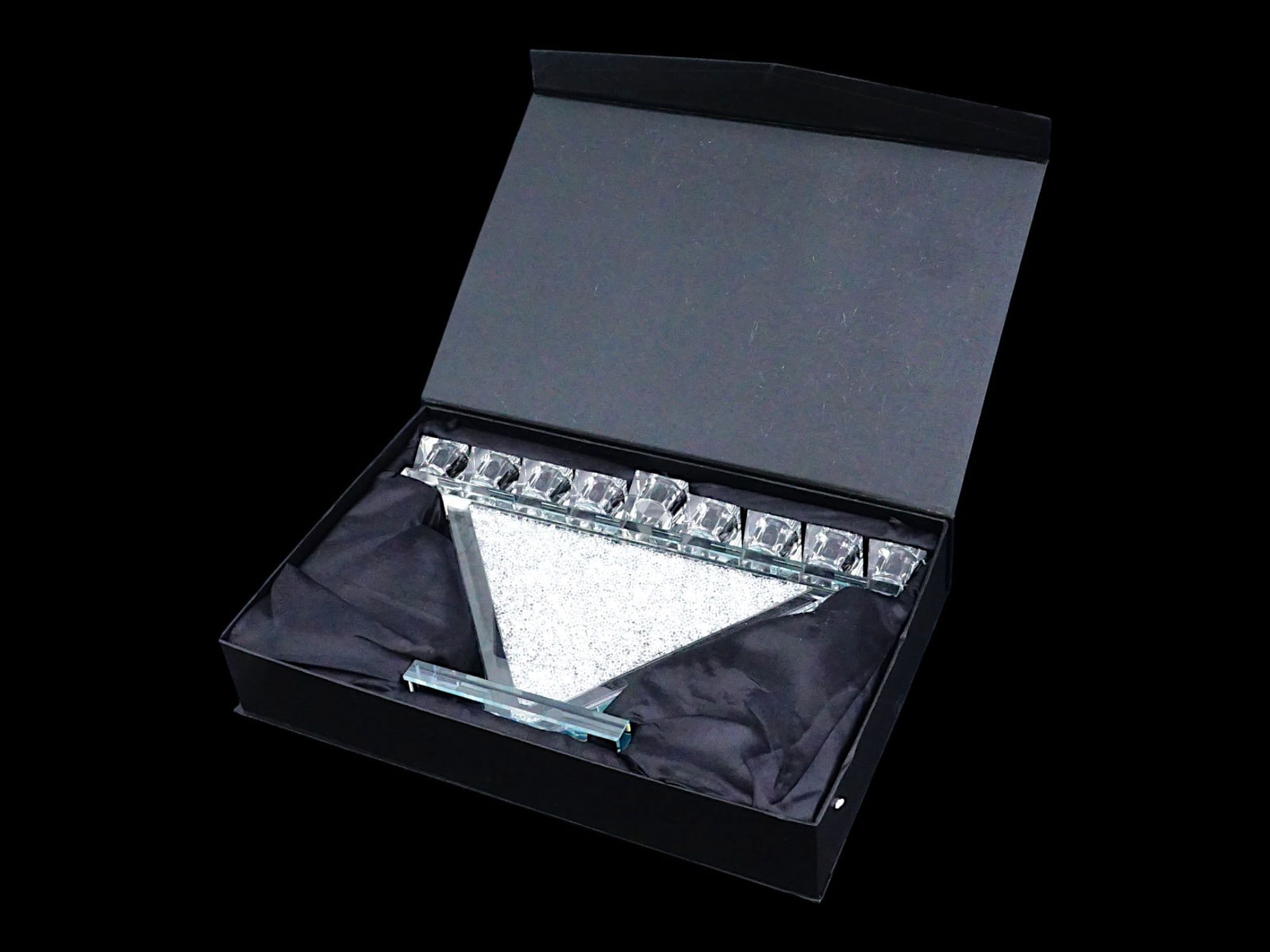 VINTAGE CRYSTAL HANUKKAH MENORAH WITH TRIANGULAR STEM: A vintage crystal Hanukkah menorah featuring a modern, elegant design. The menorah has nine candles aligned on a transparent top bar, supported by a distinctive triangular stem and base filled with lo