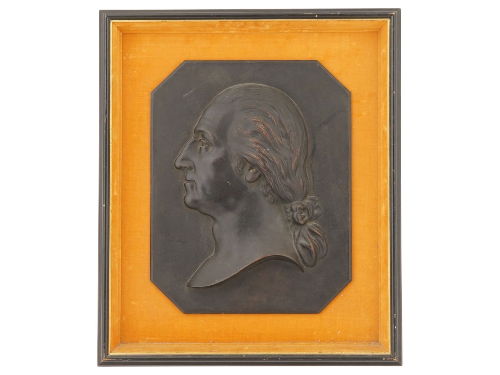 ANTIQUE AMERICAN GEORGE WASHINGTON METAL PLAQUE: An antique American metal octagonal plaque depicting a relief portrait of George Washington. Circa the 19th century. It is set against a yellow velvet background and framed by a black wooden frame. Th
