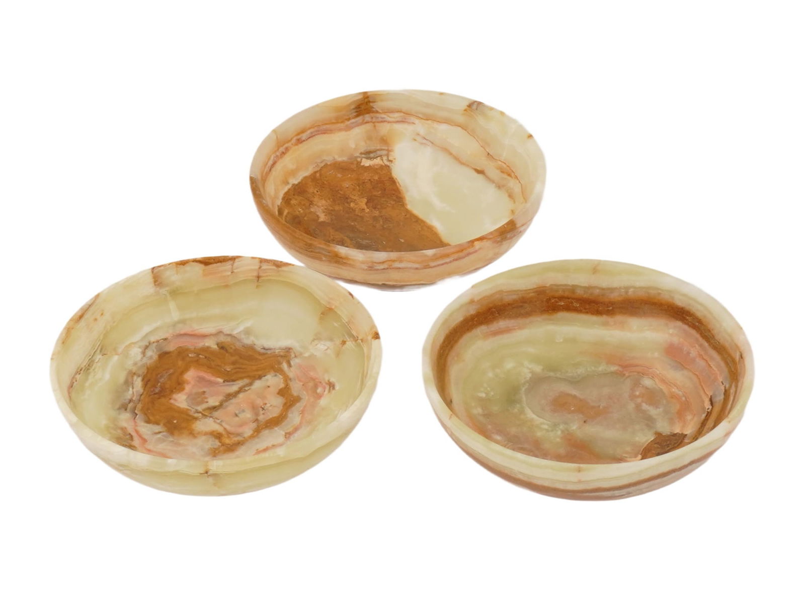 THREE VINTAGE HANDCRAFTED POLISHED ONYX BOWLS: A decorative lot of three vintage polished onyx bowls, handcrafted from natural stone and featuring distinctive banded patterns unique to each piece, suited for use as trinket dishes, catchall bowls,