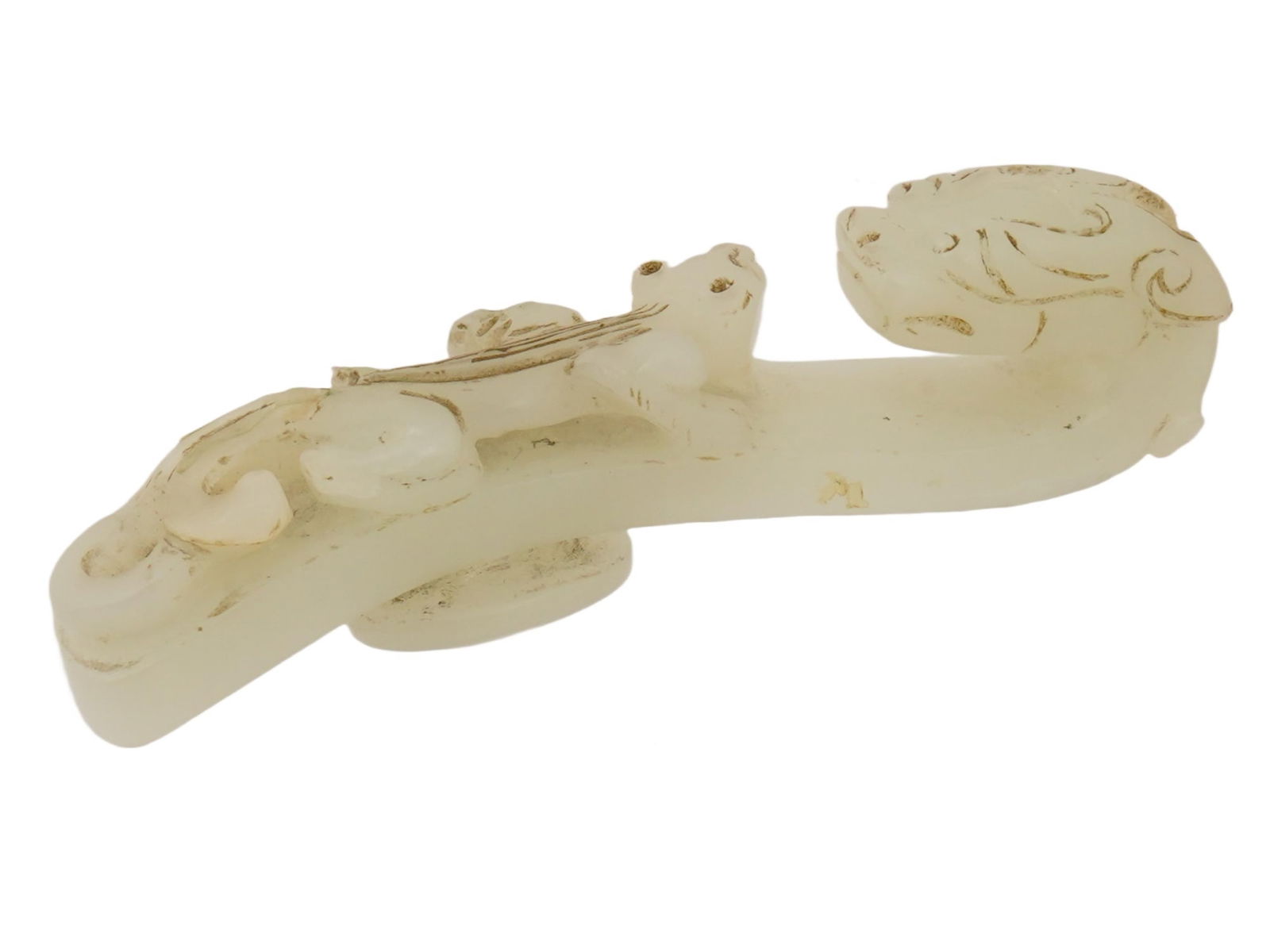 ANTIQUE CHINESE WHITE JADE BELT HOOK WITH DRAGON: An antique Chinese white jade belt hook intricately hand-carved with traditional patterns. The hook is carved in the shape of two fantastic animals, one of which is a dragon, lying facing each other.