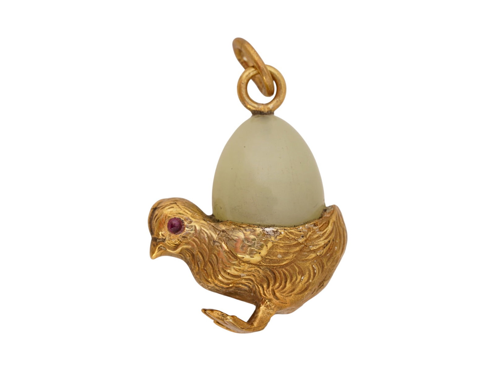 RUSSIAN GILT SILVER JADE CHICK PENDANT WITH RUBY EYES: A Russian gilt silver pendant modeled as a chick with eyes set with ruby cabochons holding a carved pale green jade egg. Finely detailed with carved patterns. Hallmarked with the 88 Russian silver
