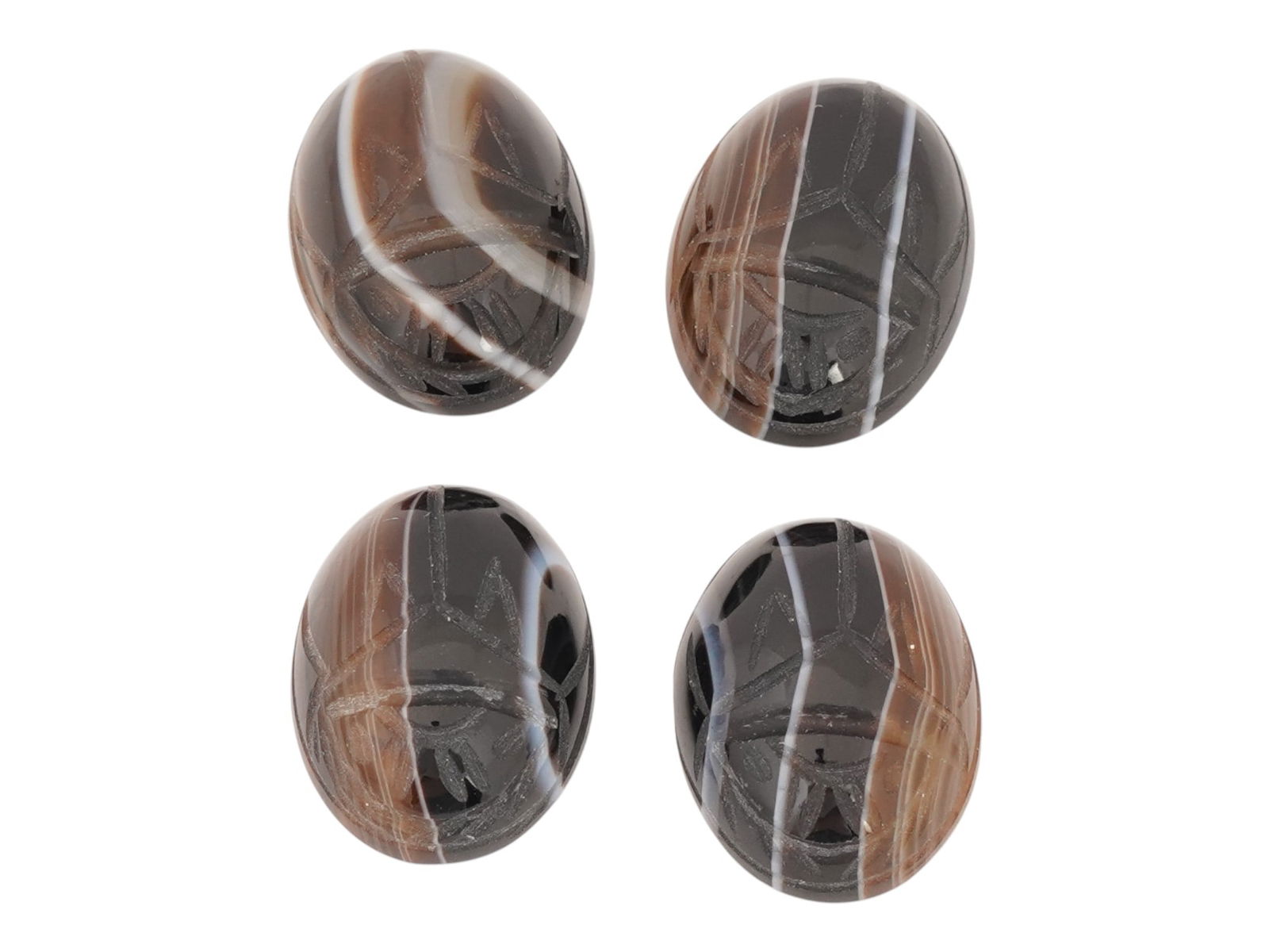 FOUR HAND CARVED DOUBLE SIDED AGATE INTAGLIOS: A lot of four hand-carved double-sided intaglios from natural stone, presumably agate. All four pieces are oval-shaped, flat on one side and convex on the other. Each piece is engraved with stylized i